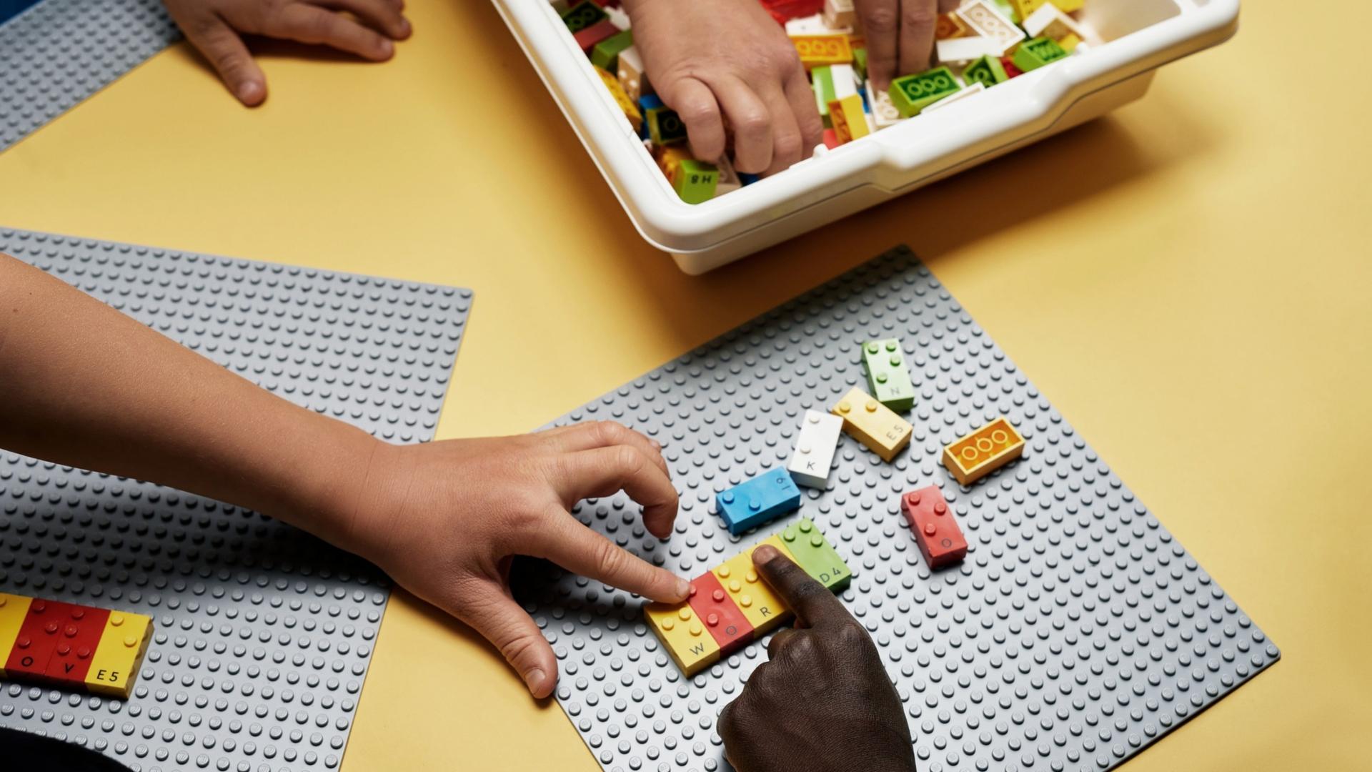 Children play with Braille Bricks on the floor as a way to learn Braille and have fun. 