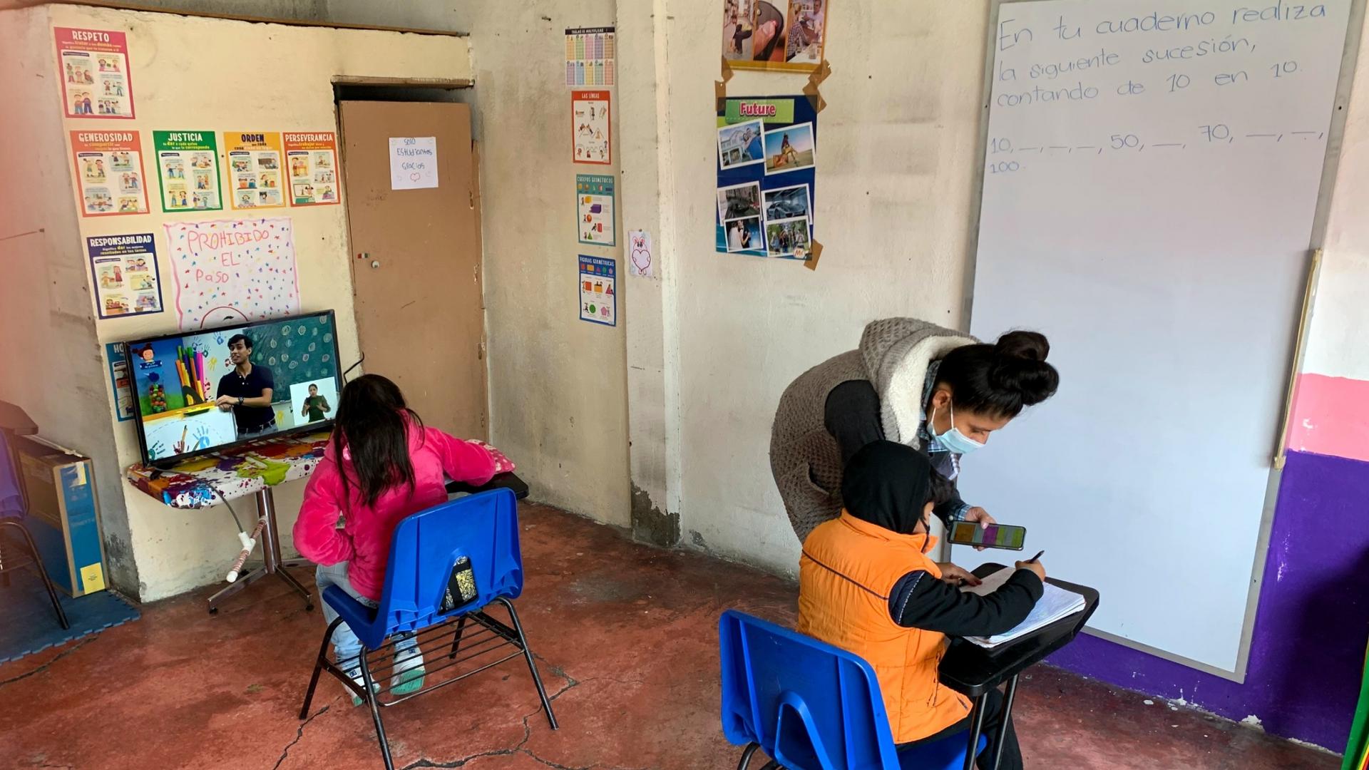 Dalia Davila, co-owner of La Abuela tortilla shop, helps Axel Carreño and Maria de la Luz Carreño at a space for students to use the internet and television for schooling.