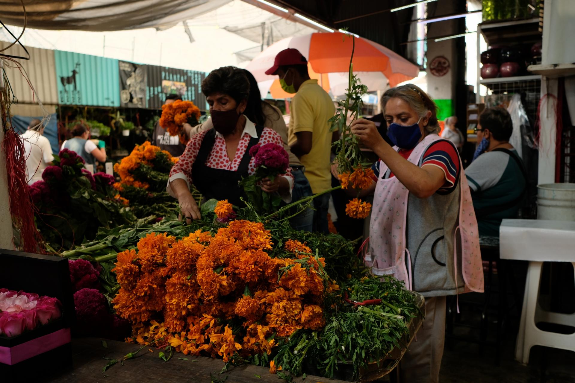 Flower vendors prep freshly harvested marigolds to sell. Many vendors agree that this year sales are very slow.