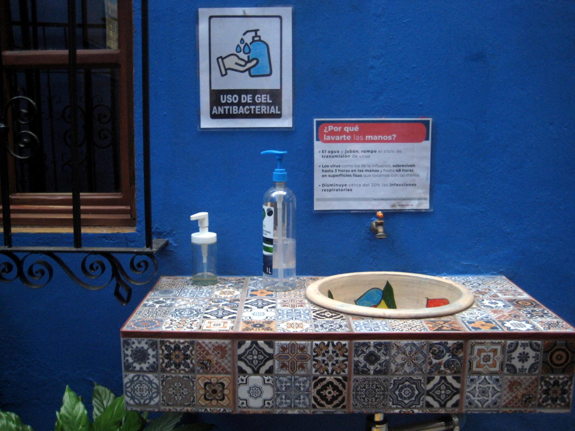 Hygiene station at the entrance of Las Golondrinas Hotel include a sink for hand-washing and a bottle with antibacterial gel. 