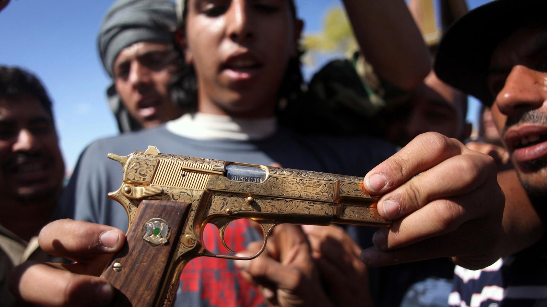 Mohammed al-Babi holds a golden pistol he says belonged to Muammar Gadhafi in Sirte, Libya.
