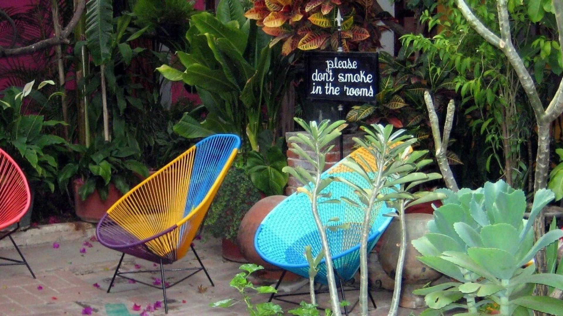 A colorful patio with chairs and greenery and a no-smoking sign