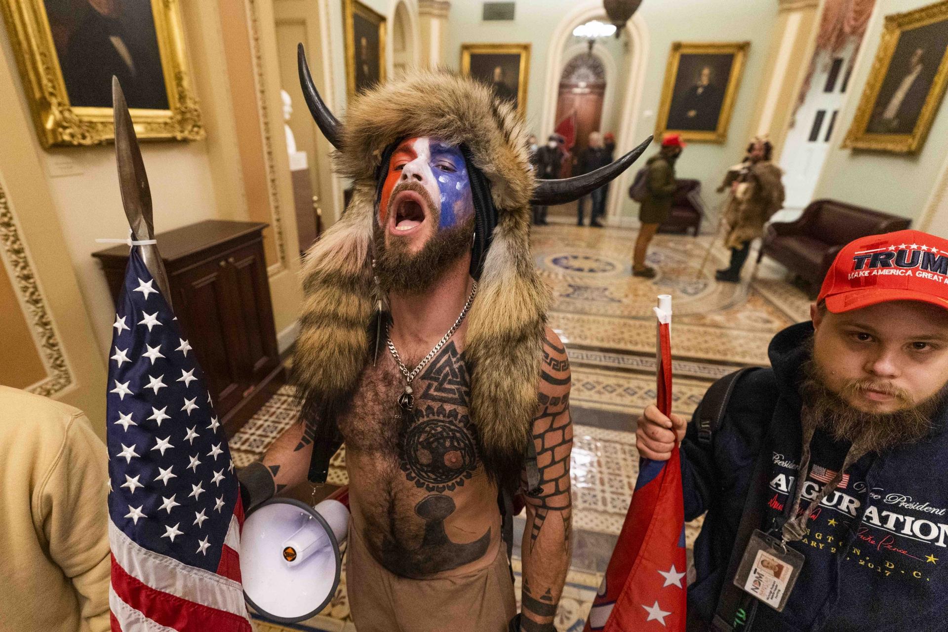 A supporter of President Donald Trump wearing horns and animal skins on his head chants outside the Senate chamber inside the Capitol, Wednesday, Jan. 6, 2021, in Washington, DC.