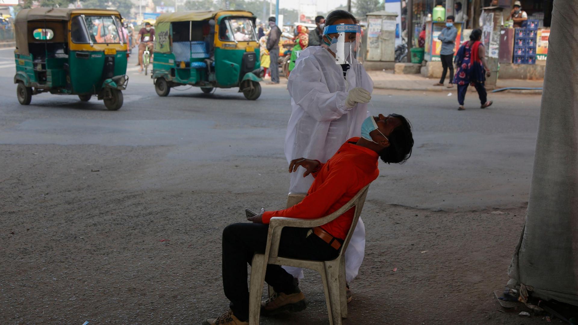 A man is shown sitting with his head back and a medical professional taking a nasal swab from his nose.