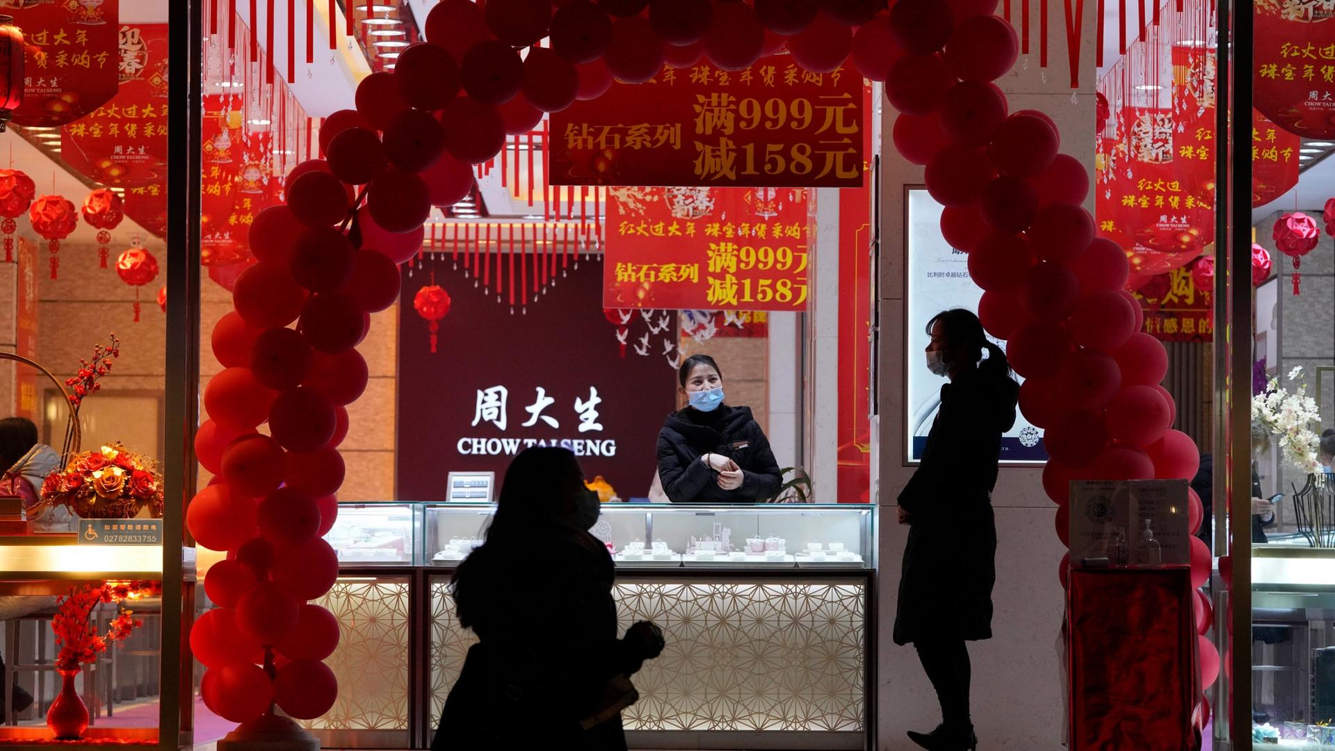 The the front window of jewelry store is shown framed by an arc of red balloons.