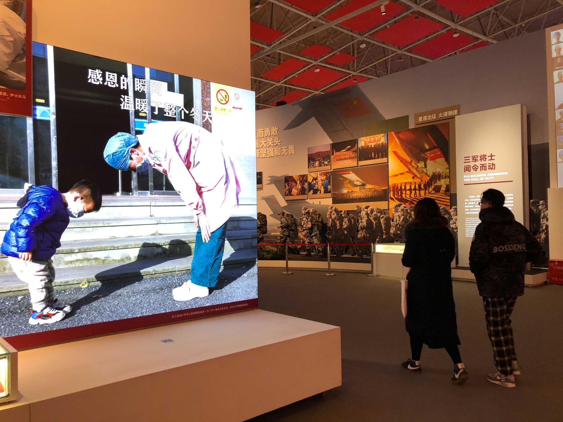 Visitors at the COVID-19 Exhibition in Wuhan, China, get a closer look at photos on display.