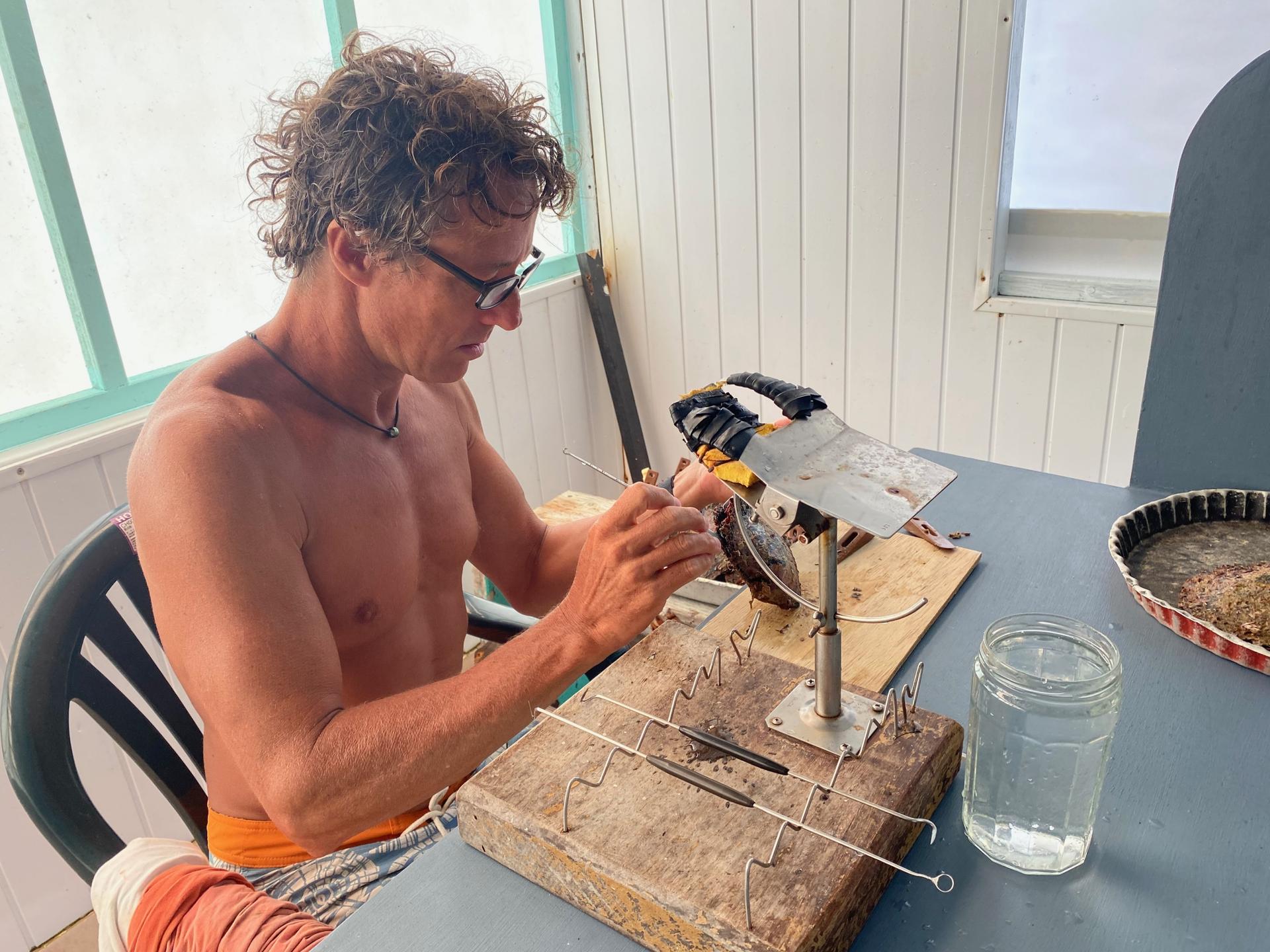 Kamoka Pearl Farm owner Josh Humbert uses a small spatula and scalpel to extract a cultured pearl from a newly cleaned oyster. 