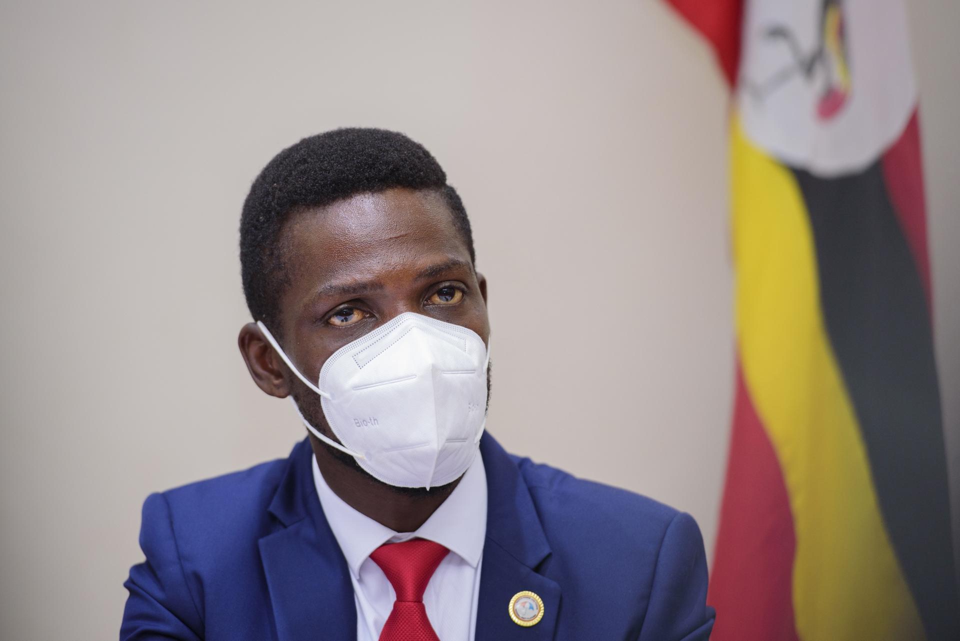 Bobi Wine, during a press conference in Kampala Uganda, Tuesday, Jan.12, 2021, wears a white face mask and blue suit with red tie. 