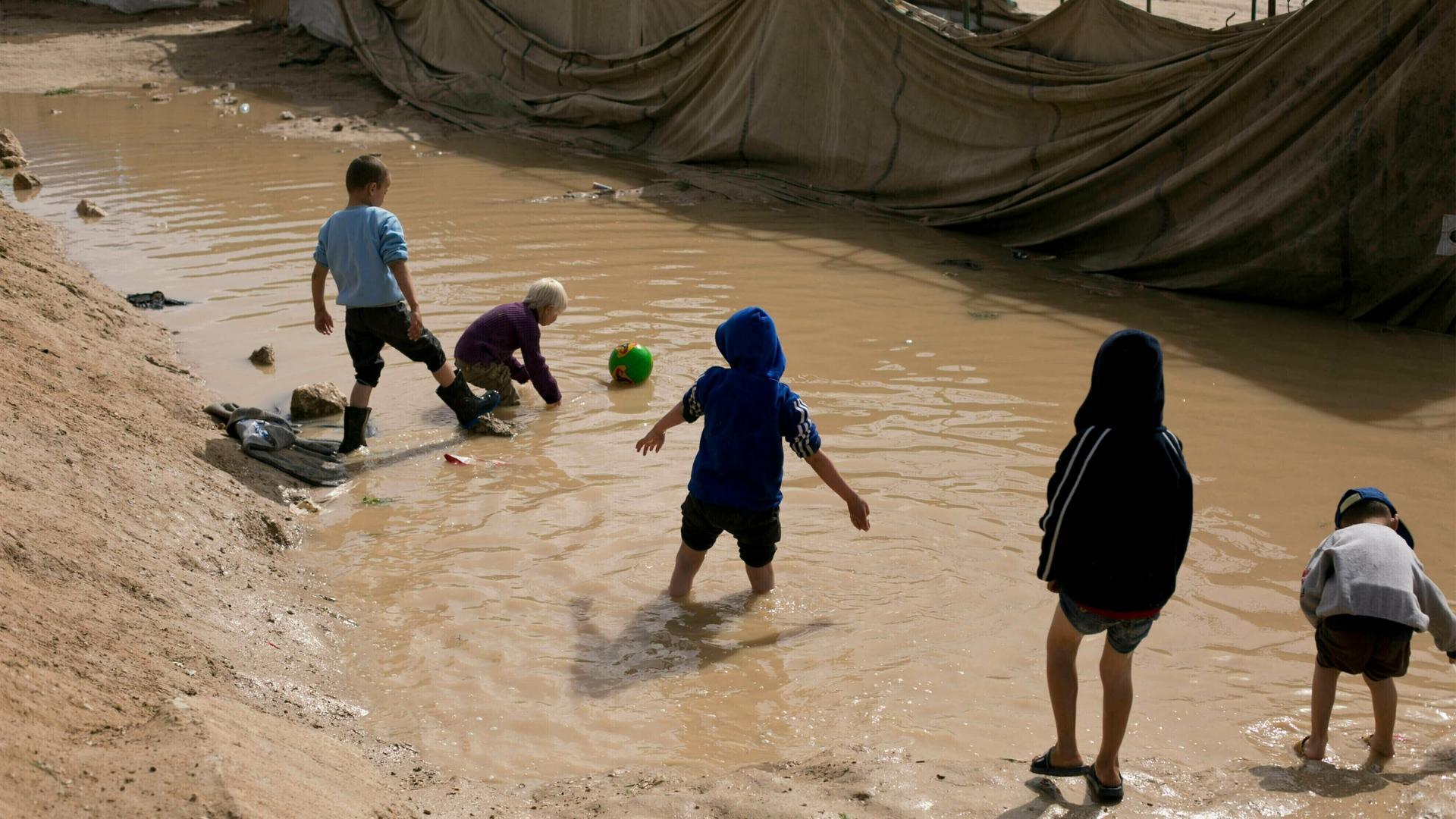 Children play in a mud puddle in the section for foreign families at Al-Hol camp in Hasakeh province, Syria on March 31, 2019.