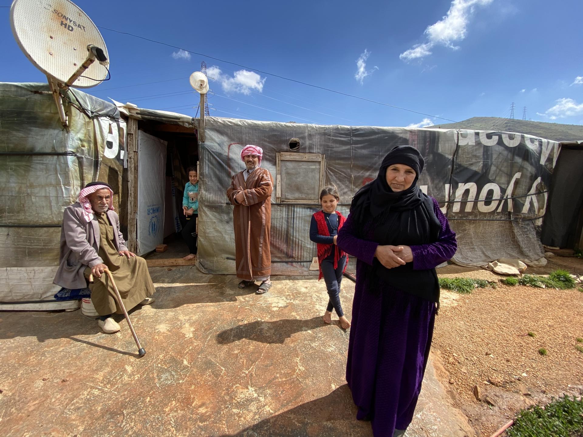 Bashil el-Ahmad in front of her tent with her family. The mountains behind mark the Syrian border. 