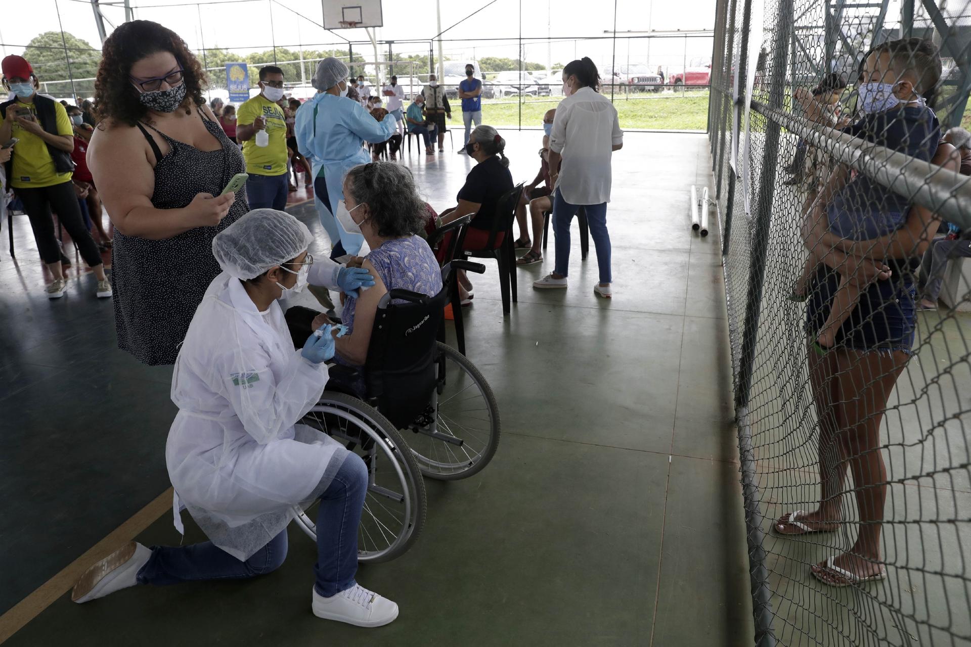 A health worker inoculates a woman at a COVID-19 vaccination point for priority elderly persons in the Ceilandia neighborhood, on the outskirts of Brasilia, Brazil, March 22, 2021.