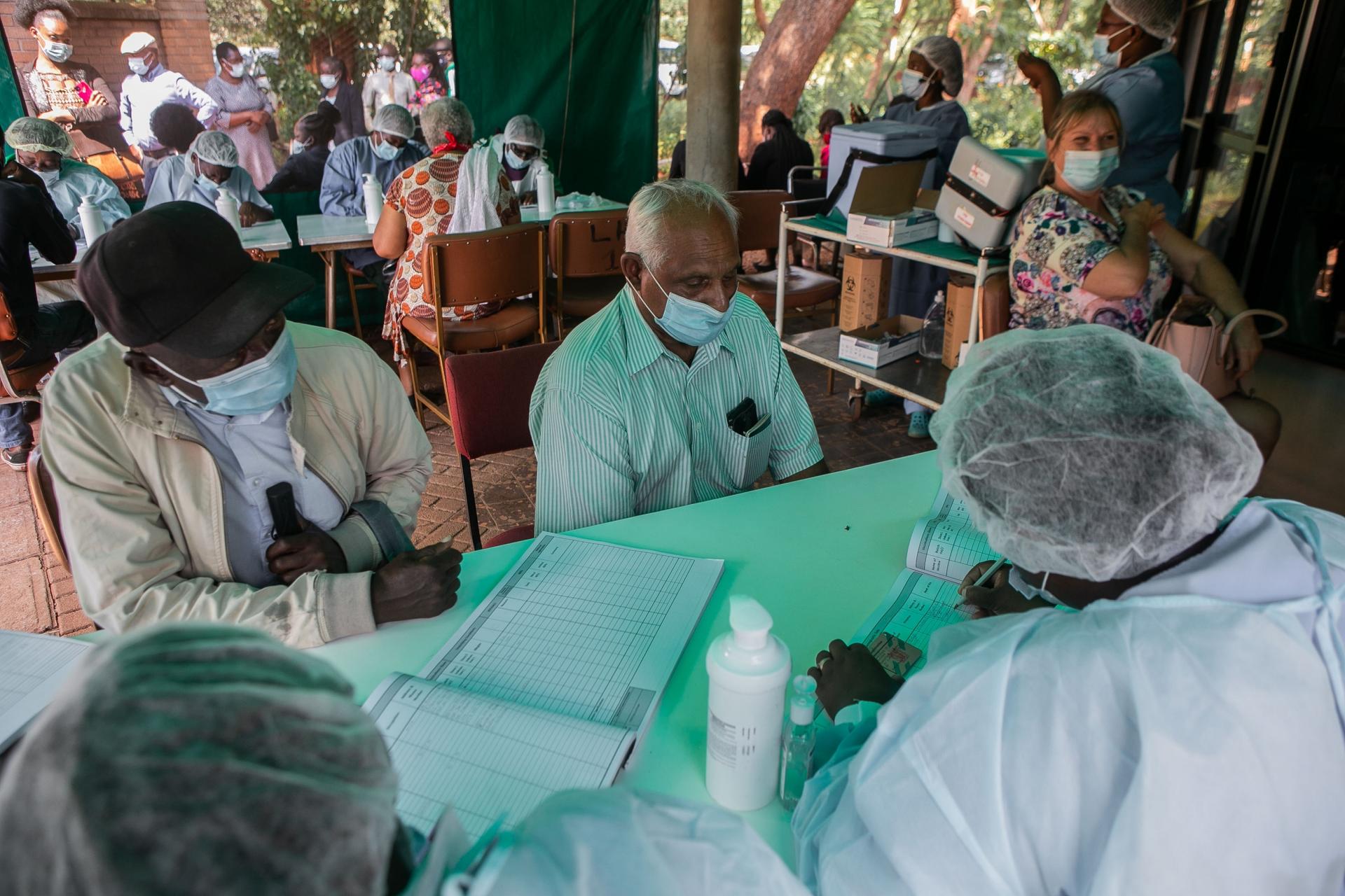 Citizens receive vaccinations with PPE-wearing health workers