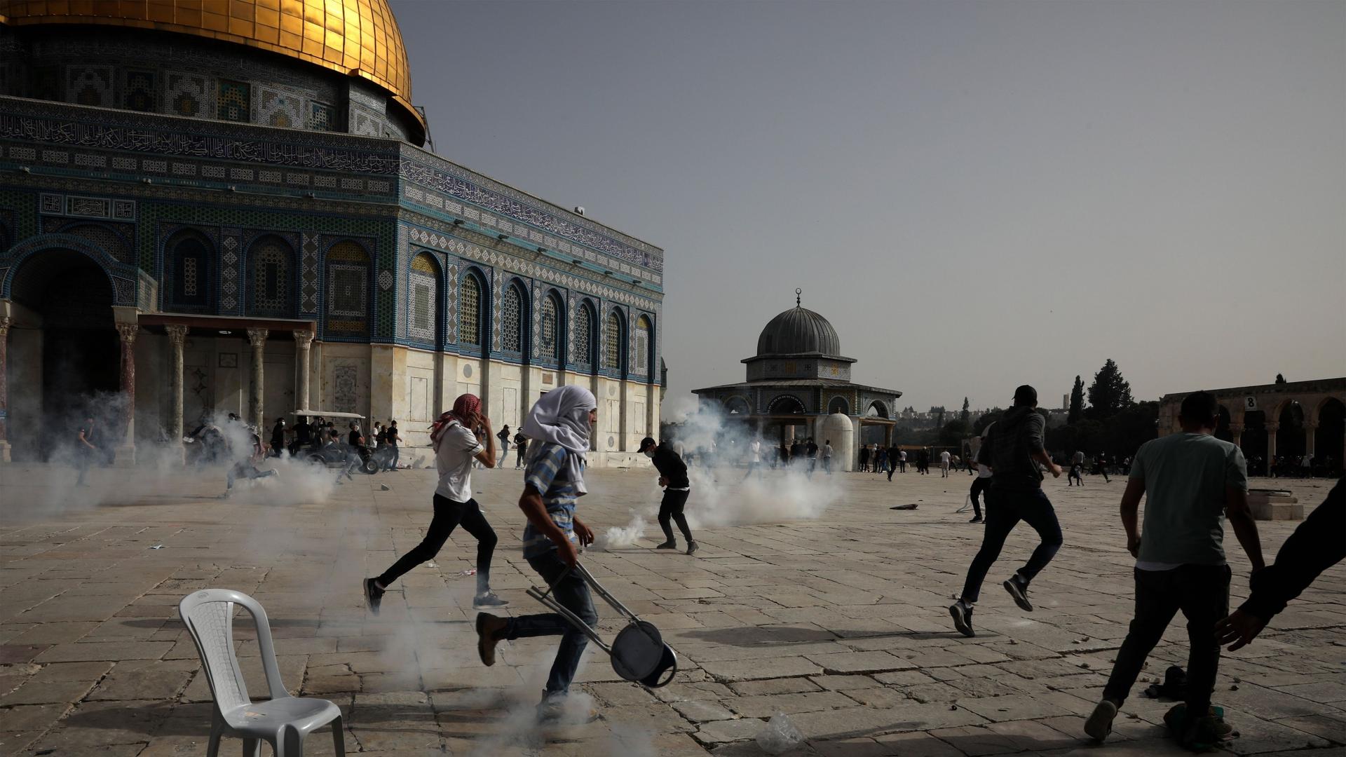 Palestinians run away from tear gas during clashes with Israeli security forces at the Al-Aqsa Mosque compound in Jerusalem's Old City Monday, May 10, 2021.