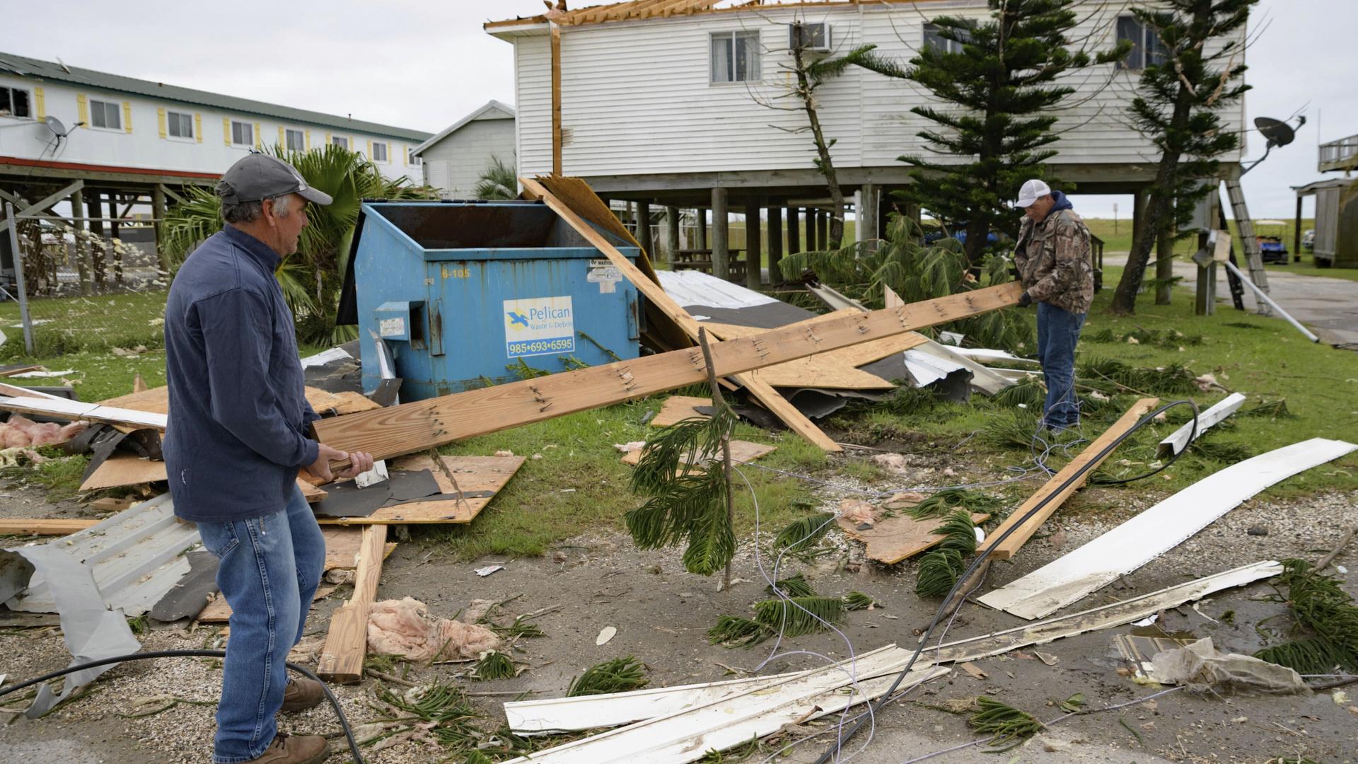 In this Oct. 30, 2020, file photo, Mark Andollina, left, and Shane Holder, remove part of a roof damaged by Hurricane Zeta 