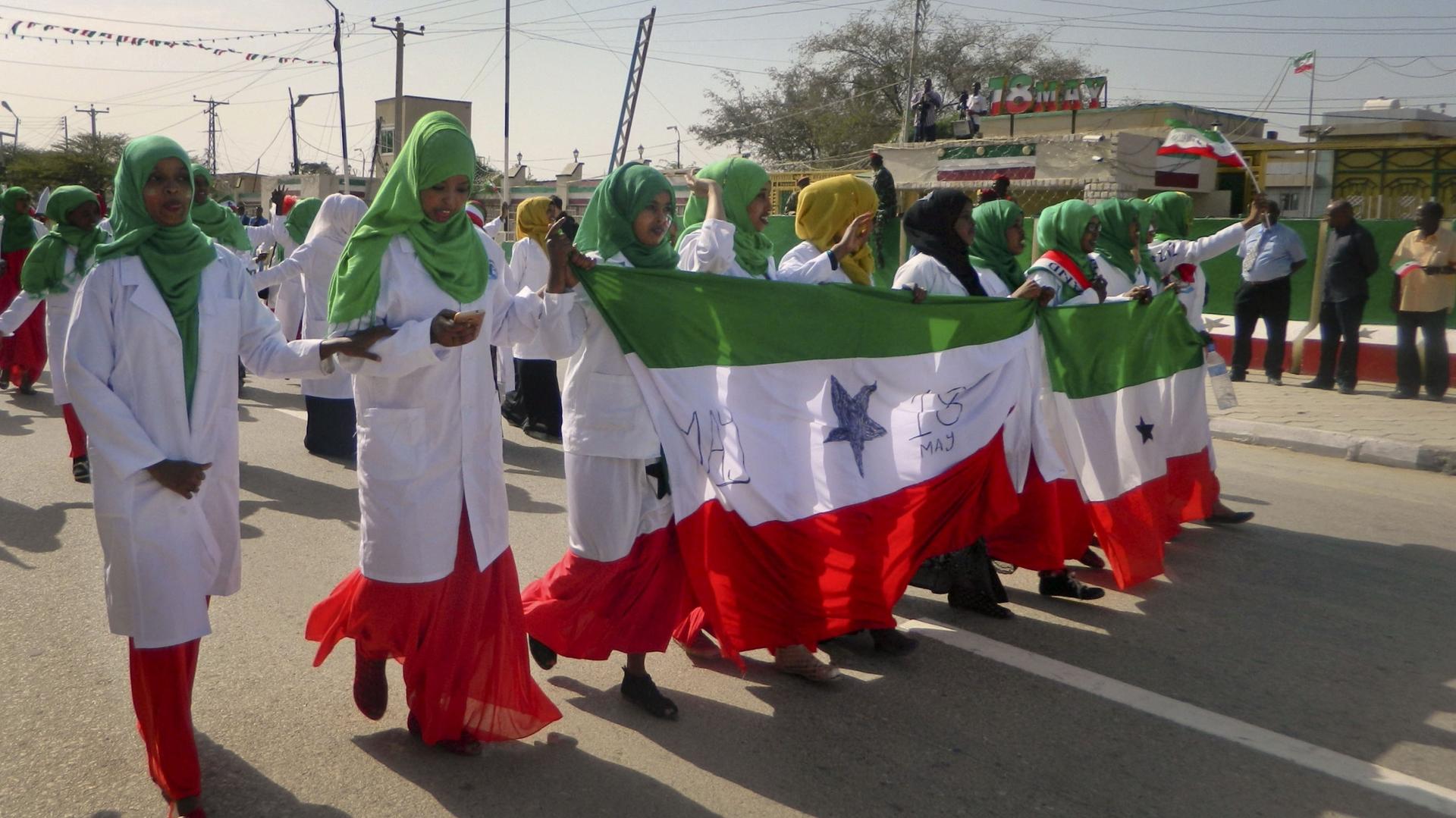 Women wear red, white, and green clothes and march in a parade celebrating independence. 