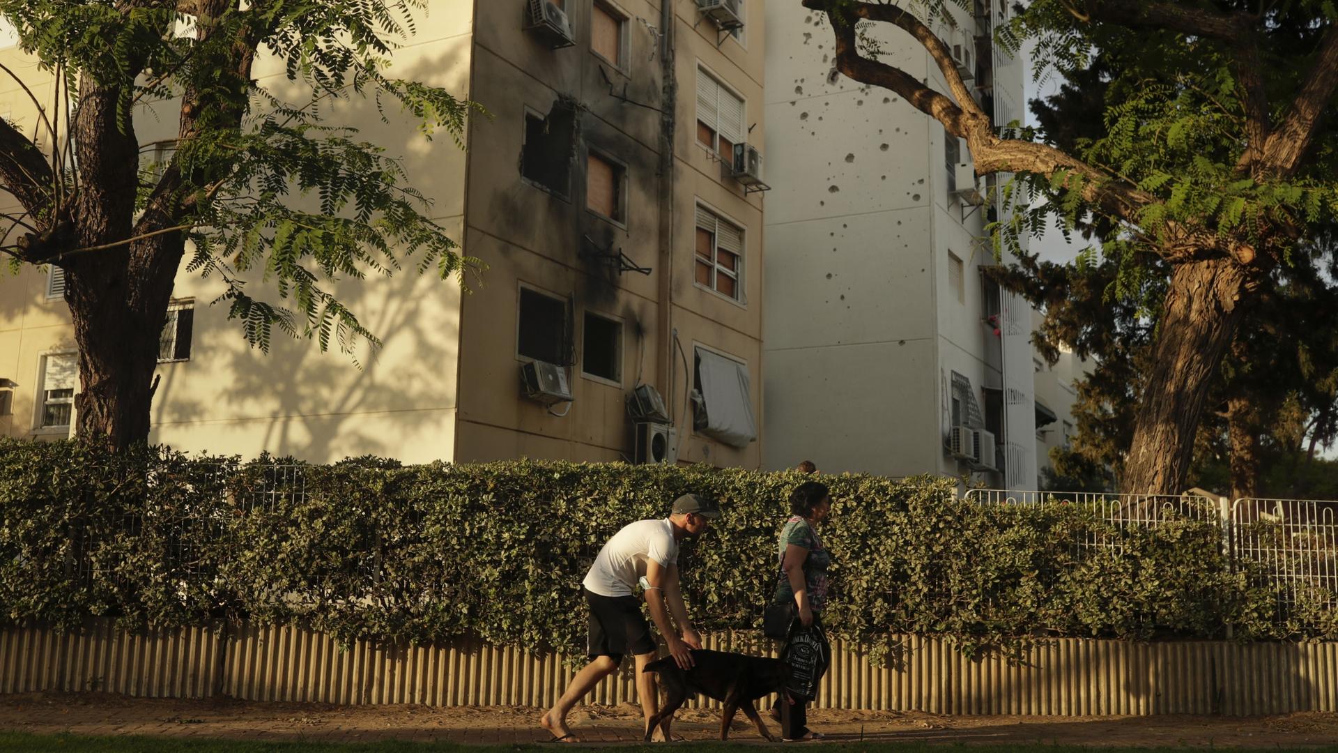 People walk by a damaged residential building after it was hit by a rocket fired from the Gaza Strip. 