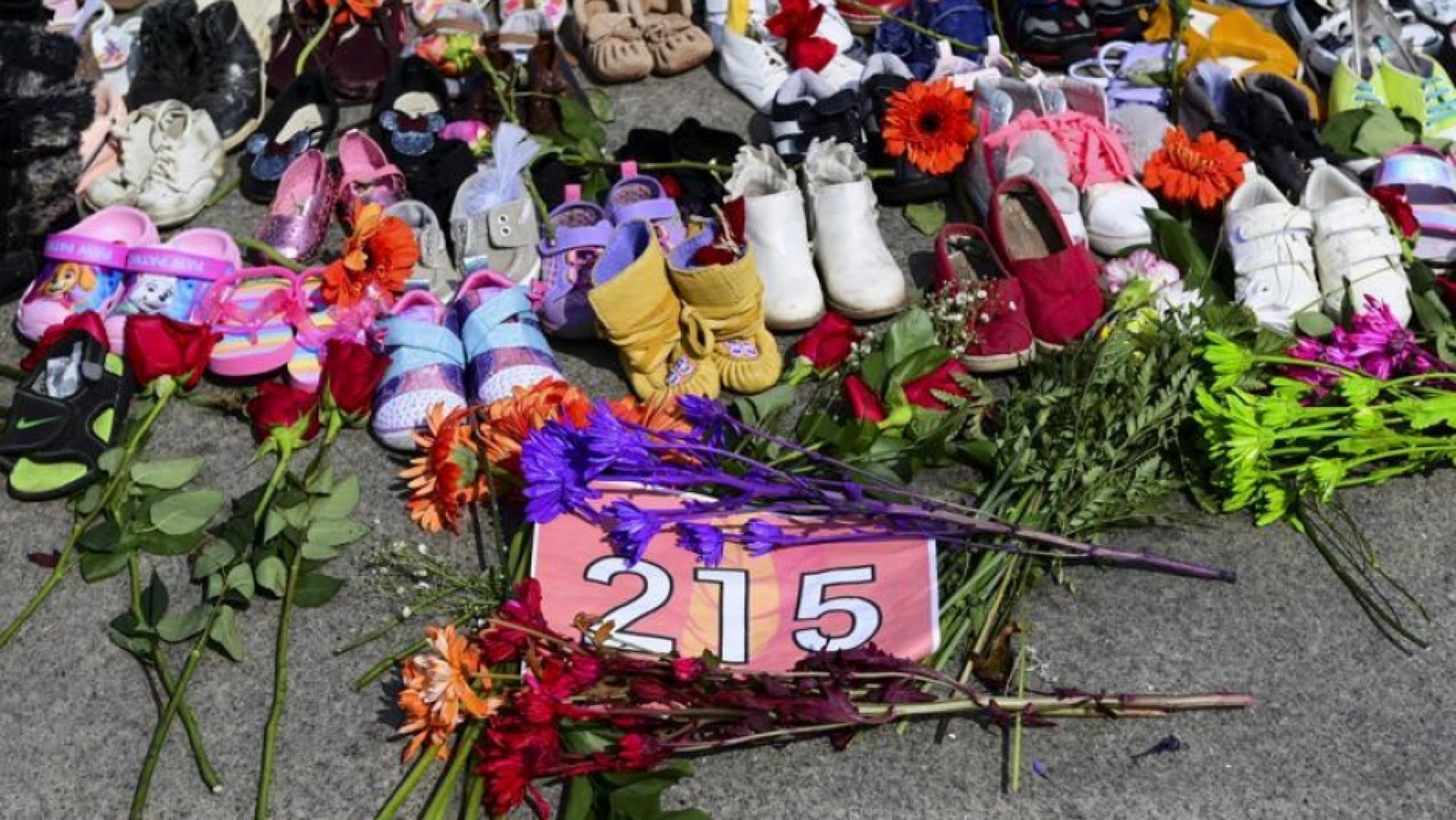 Flowers, children's shoes and other items rest at a memorial at the Eternal Flame on Parliament Hill in Ottawa