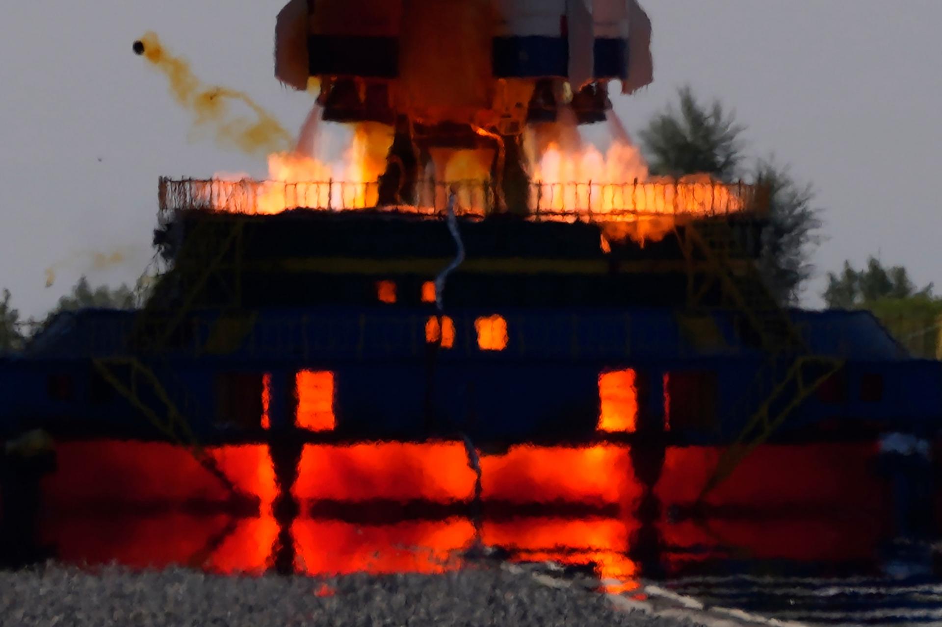 A close up photograph shows fire coming out of the exhaust of the rockets carrying the Chinese spaceship.