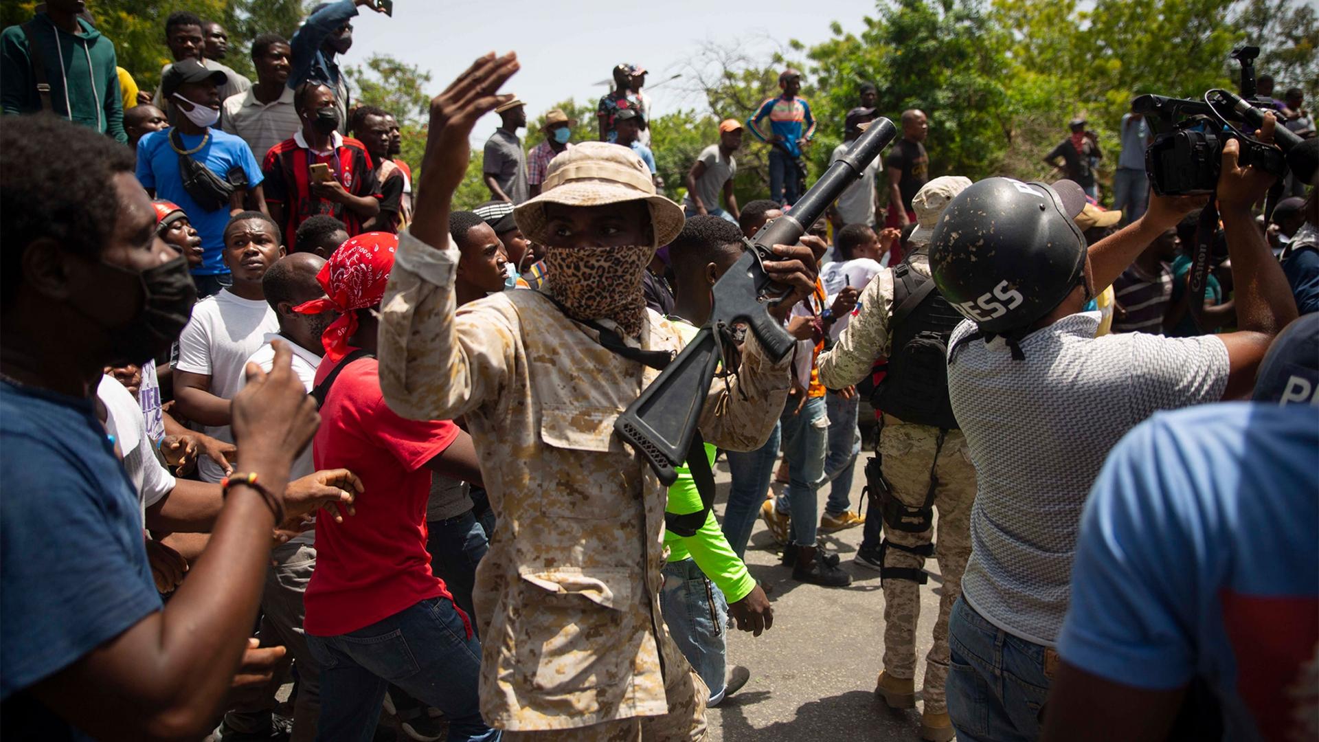 Police in camouflage stand amid a crowd protesting against the assassination of Haitian President Jovenel Moïse