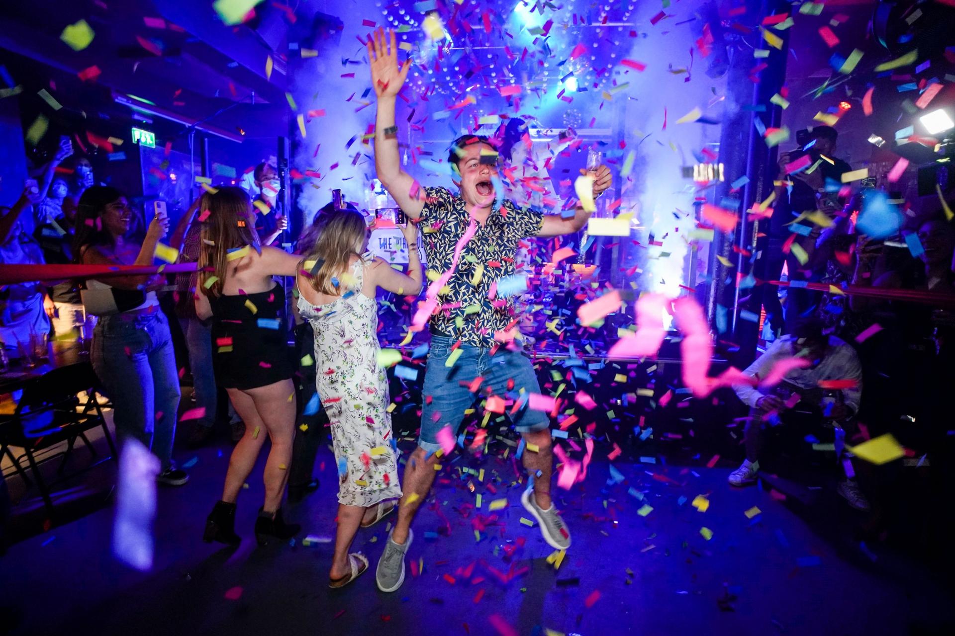 A man is shown jumping in the air amid colorful confetti flying all around.