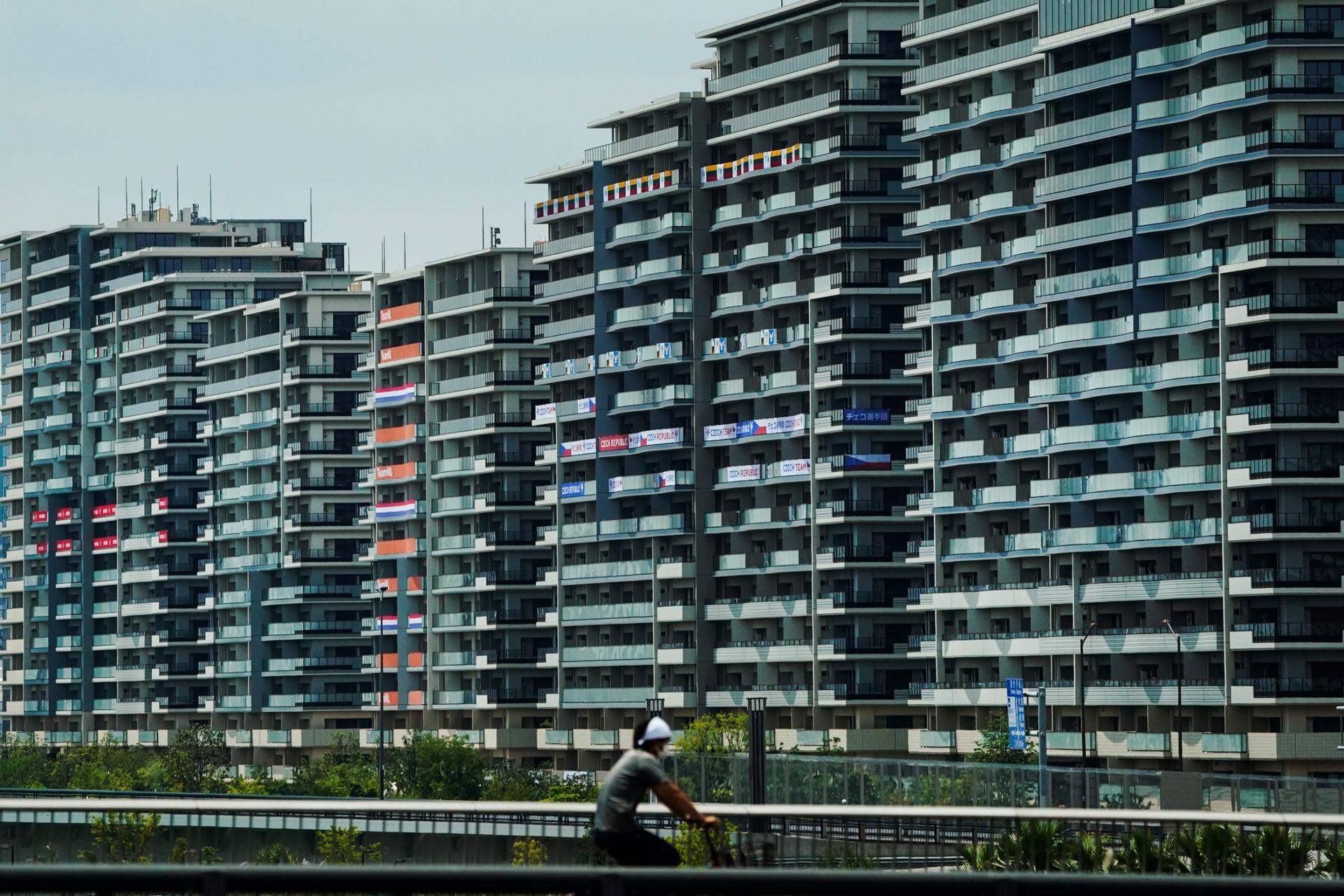 A row of tall buildings are shown, many with national flags hanging from the balconies.