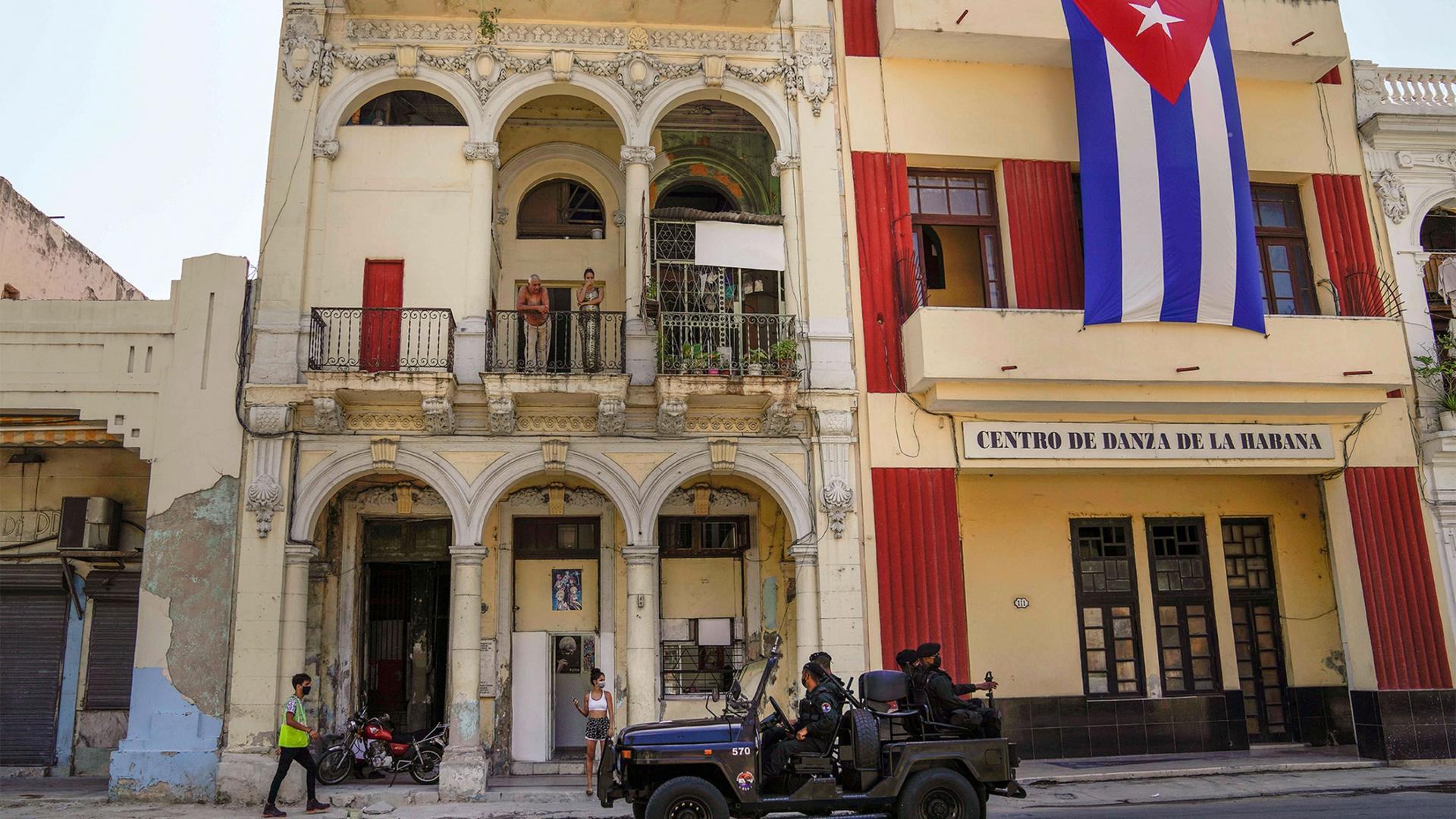 Special forces police patrol the streets as they drive past a large Cuban flag hanging from the facade of a building, in Havana, Cuba