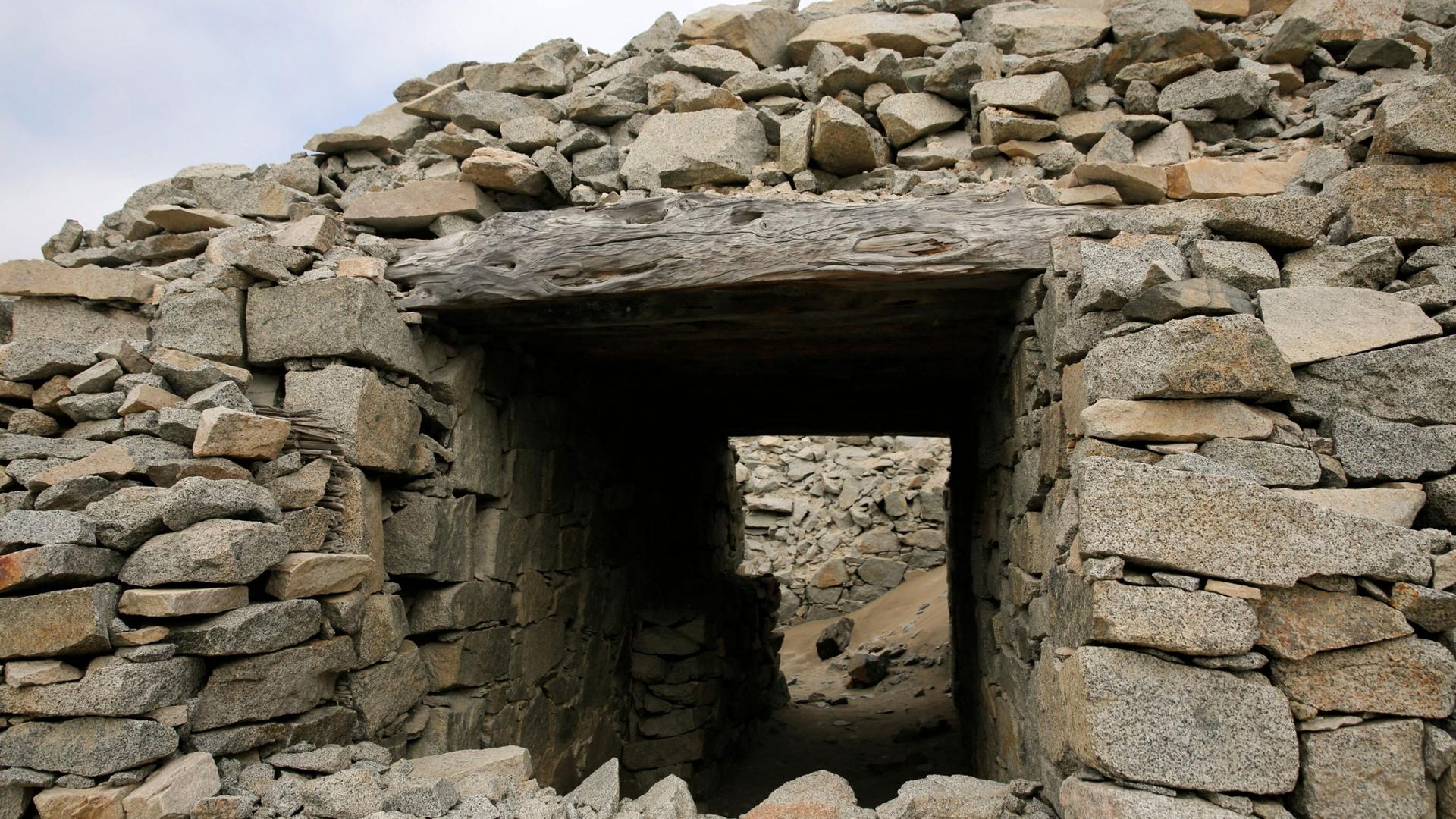 A large pile of stones are shown with a square opening and a passageway.