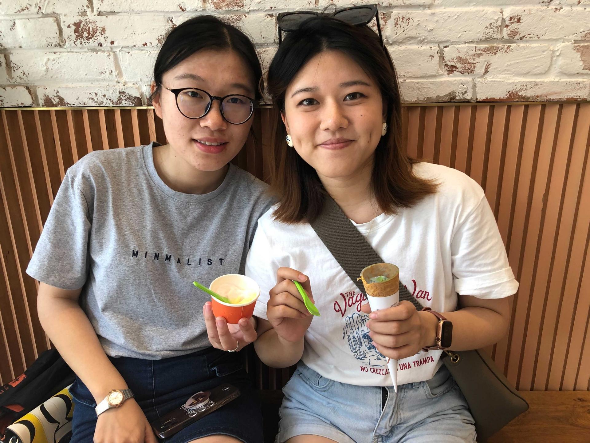Two women smile for the camera while holding ice cream