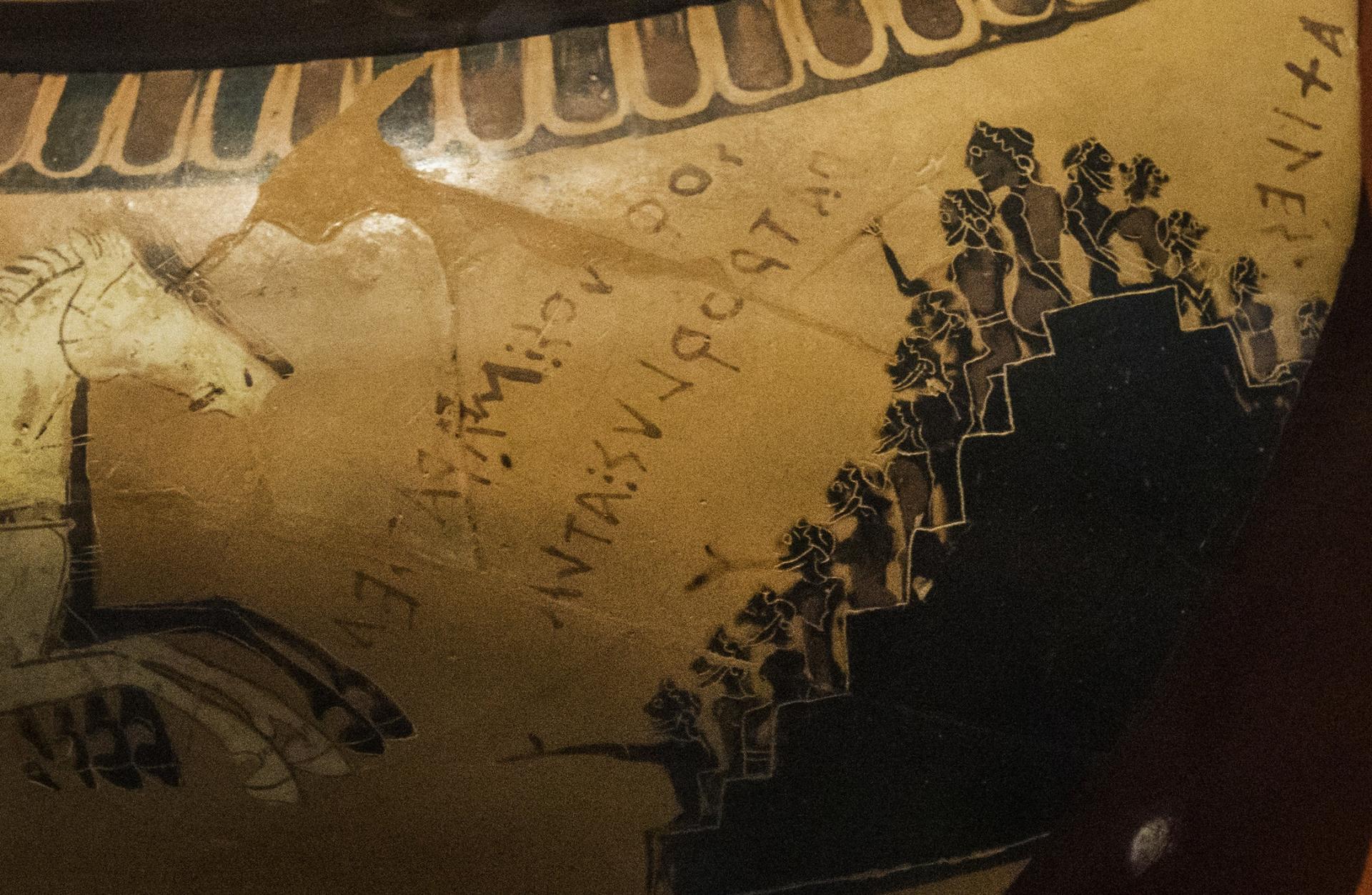 A detail of a Greek cauldron depicts spectators cheering on a chariot race. 