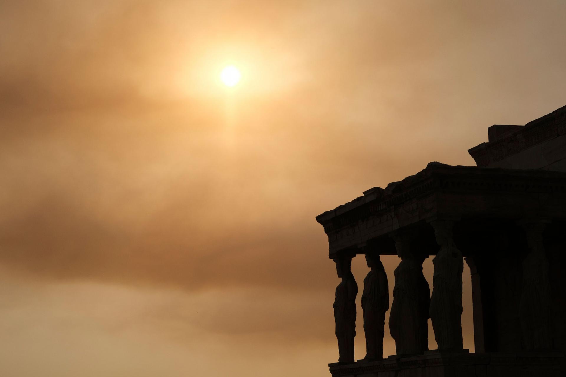 The columns of the Acropolis are shown in shadown with the sun in the distance blocked by smoke clouds.