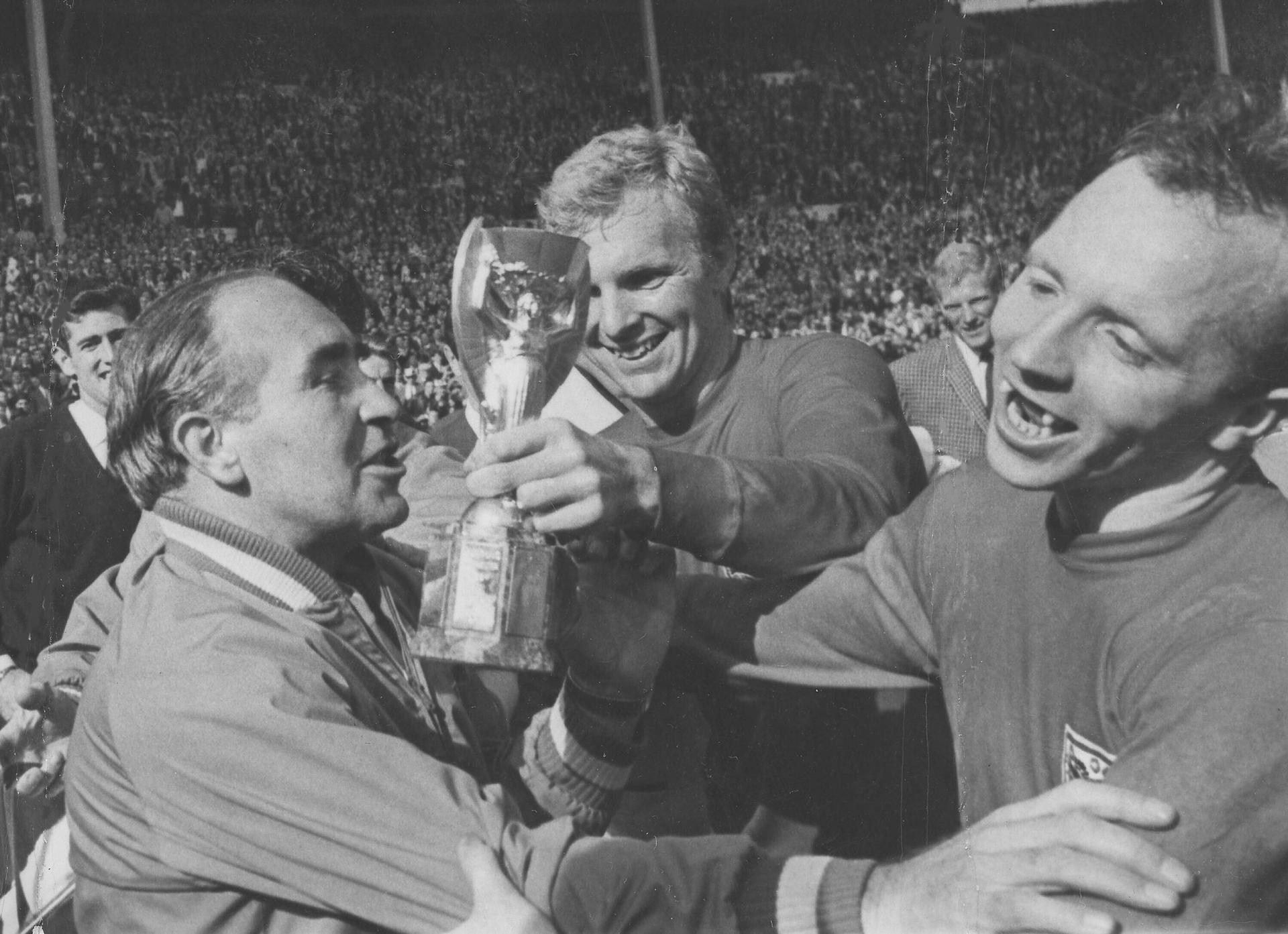 In this July 30, 1966 file photo, England midfield player Nobby Stiles, right, looks at the Jules Rimet Cup, held by England captain Bobby Moore after they had won the World Cup Final at Wembley, London.