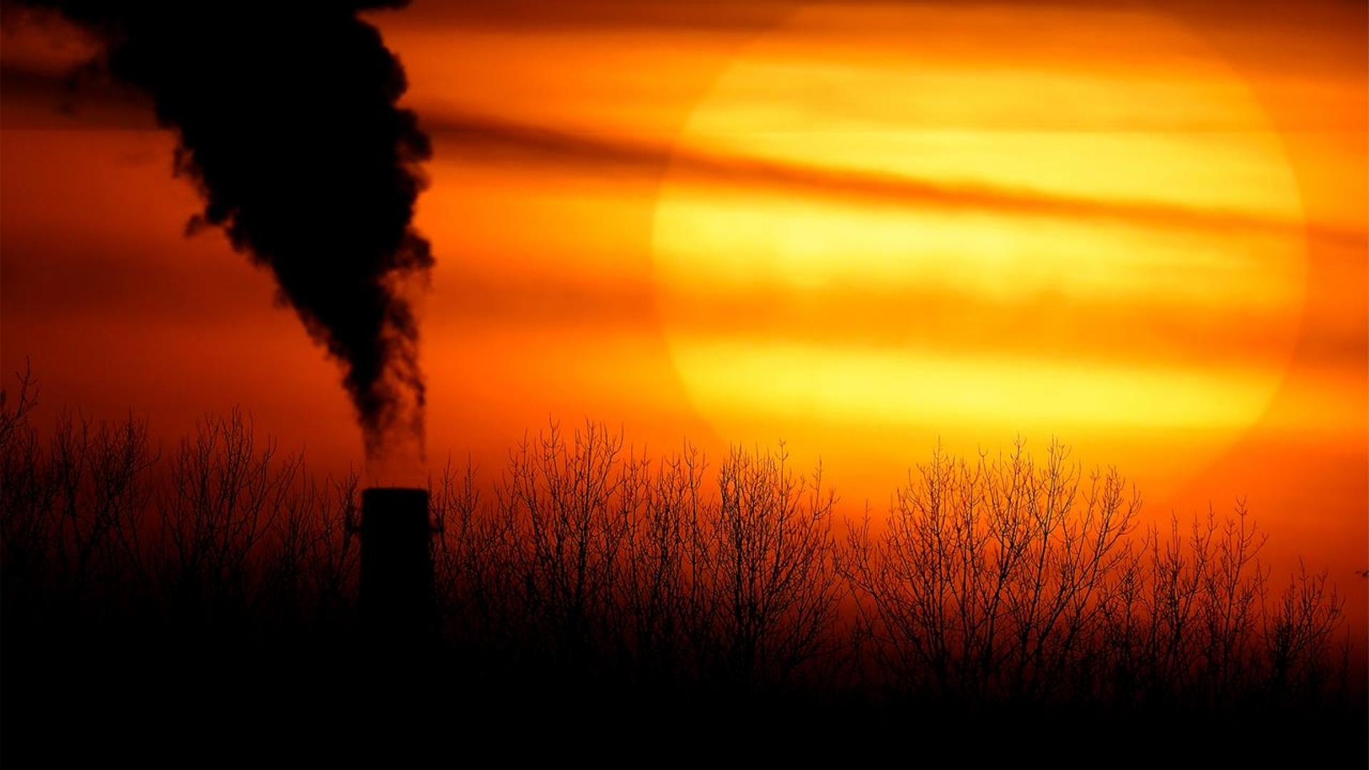 Emissions from a coal-fired power plant are silhouetted against the setting sun in Independence, Mo.
