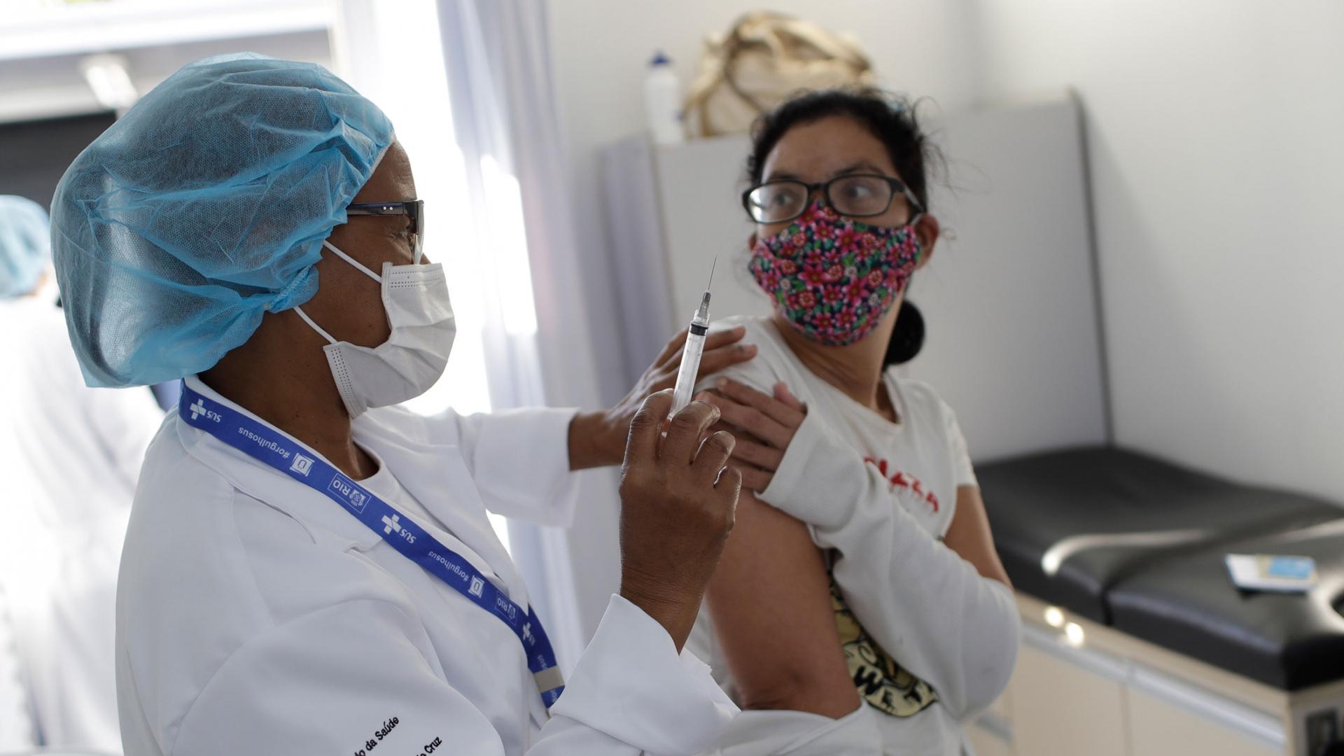 A resident gets a dose of the AstraZeneca vaccine on the first day of a three-day COVID-19 vaccination campaign for people over age 35 in the Complexo da Maré favela of Rio de Janeiro, Brazil, Brazil, Thursday, July 29, 2021. 