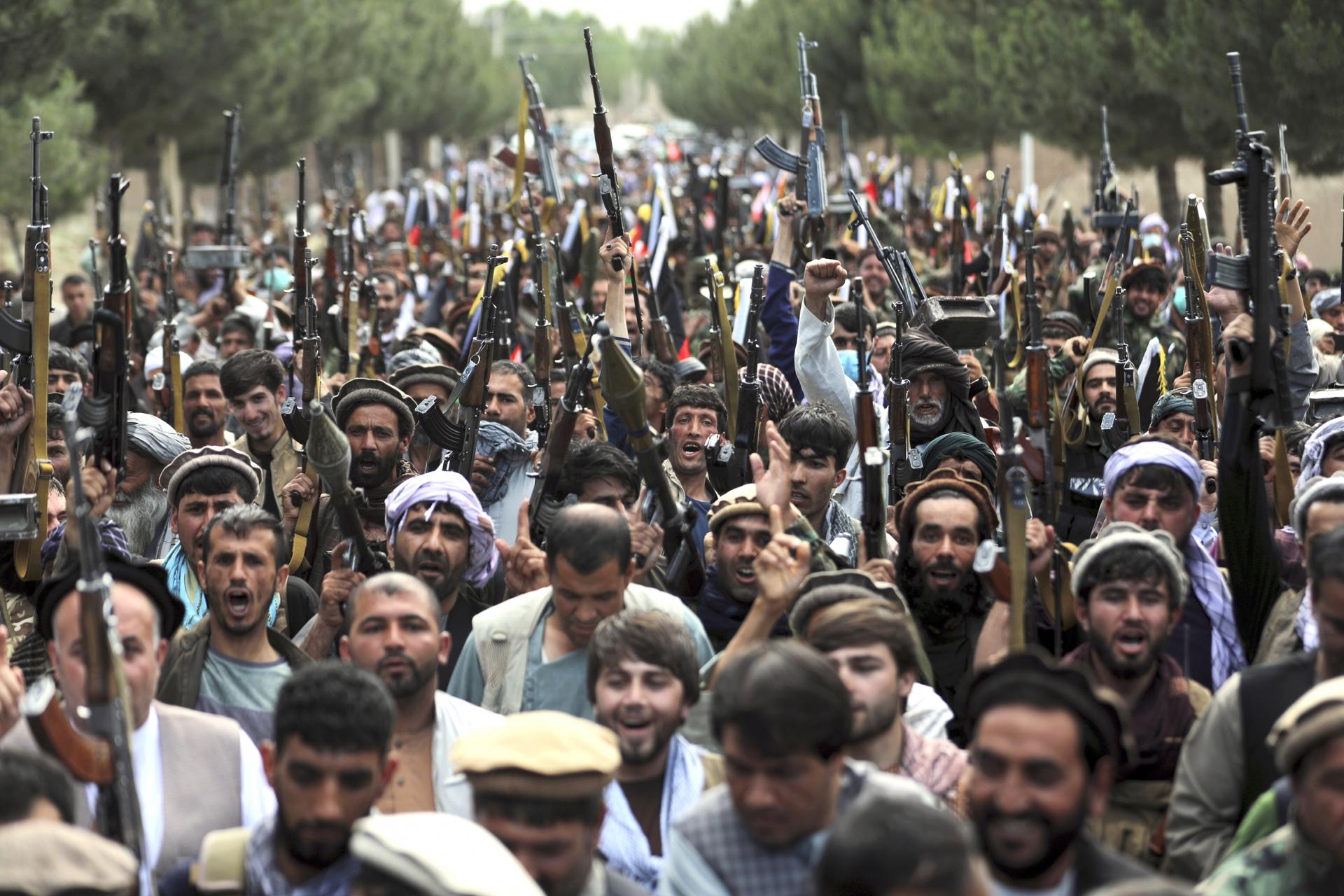 A crowd of Taliban fighters in a road, holding automatic rifles in the air