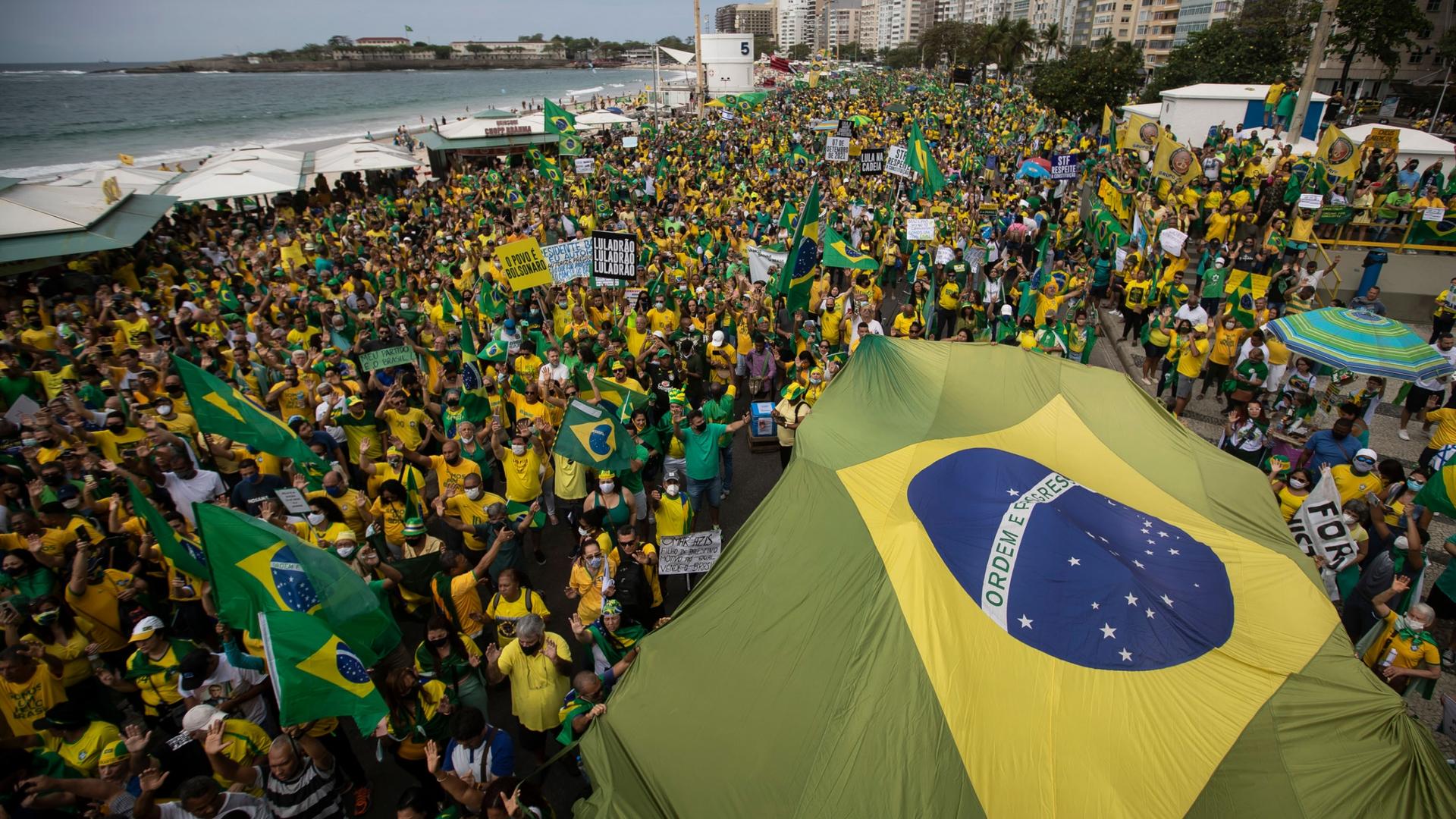 Supporters of Brazilian President Jair Bolsonaro carry Brazil's national flag along Copacabana Beach on Independence Day in Rio de Janeiro, Brazil, Tuesday, Sept. 7, 2021. 