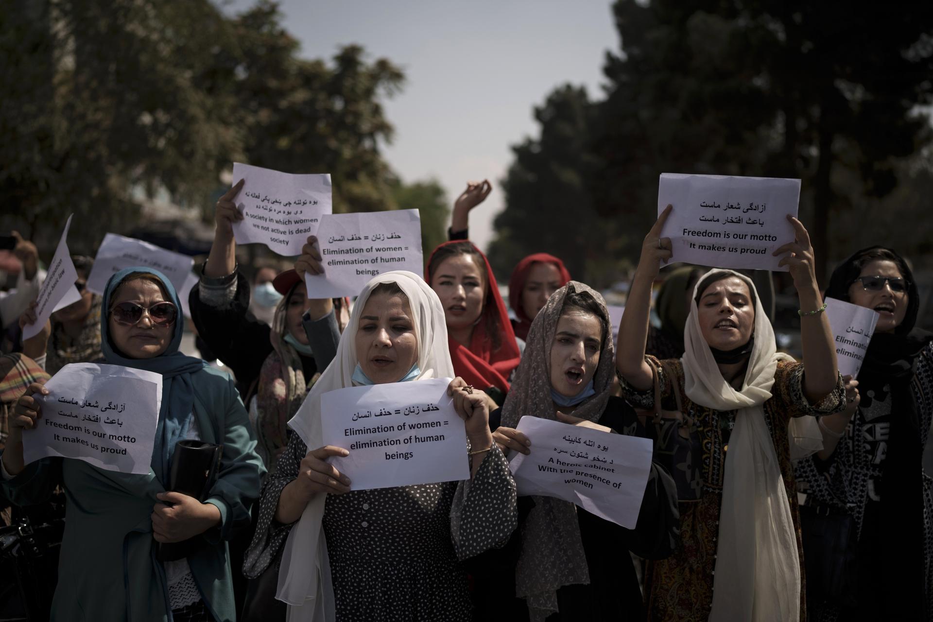 Afghan women march and hold signs in rally