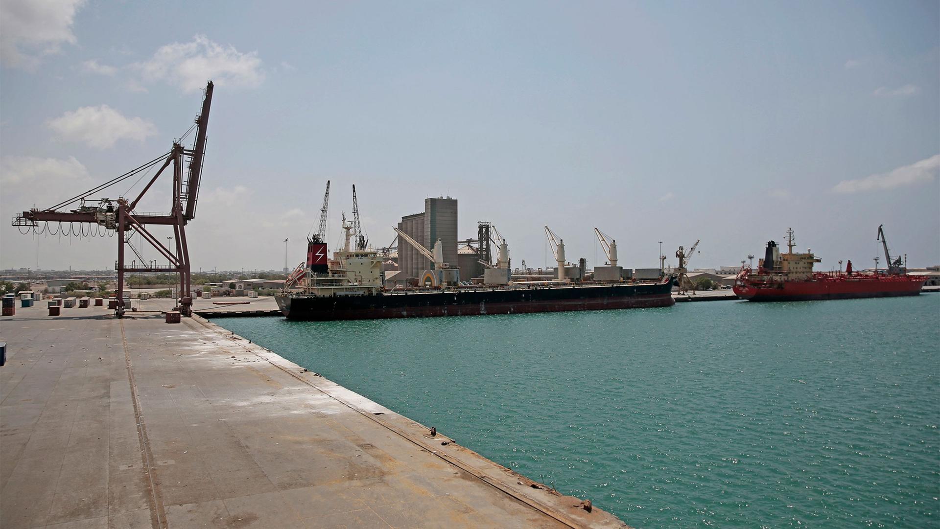 A cargo ship and oil tanker ship sit idle while docked at the port of Hodeida, Yemen