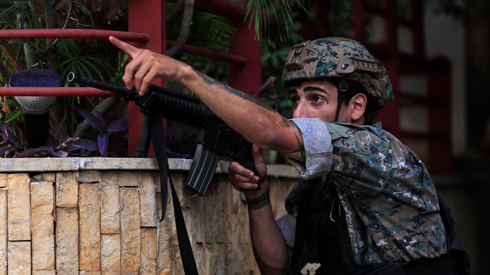 A Lebanese special forces soldier take his position, as he points to his comrades to a position of a shiite group sniper who was sniping at the Christian neighborhood of Ain el-Remaneh, in Beirut, Lebanon, Thursday, Oct. 14, 2021. 