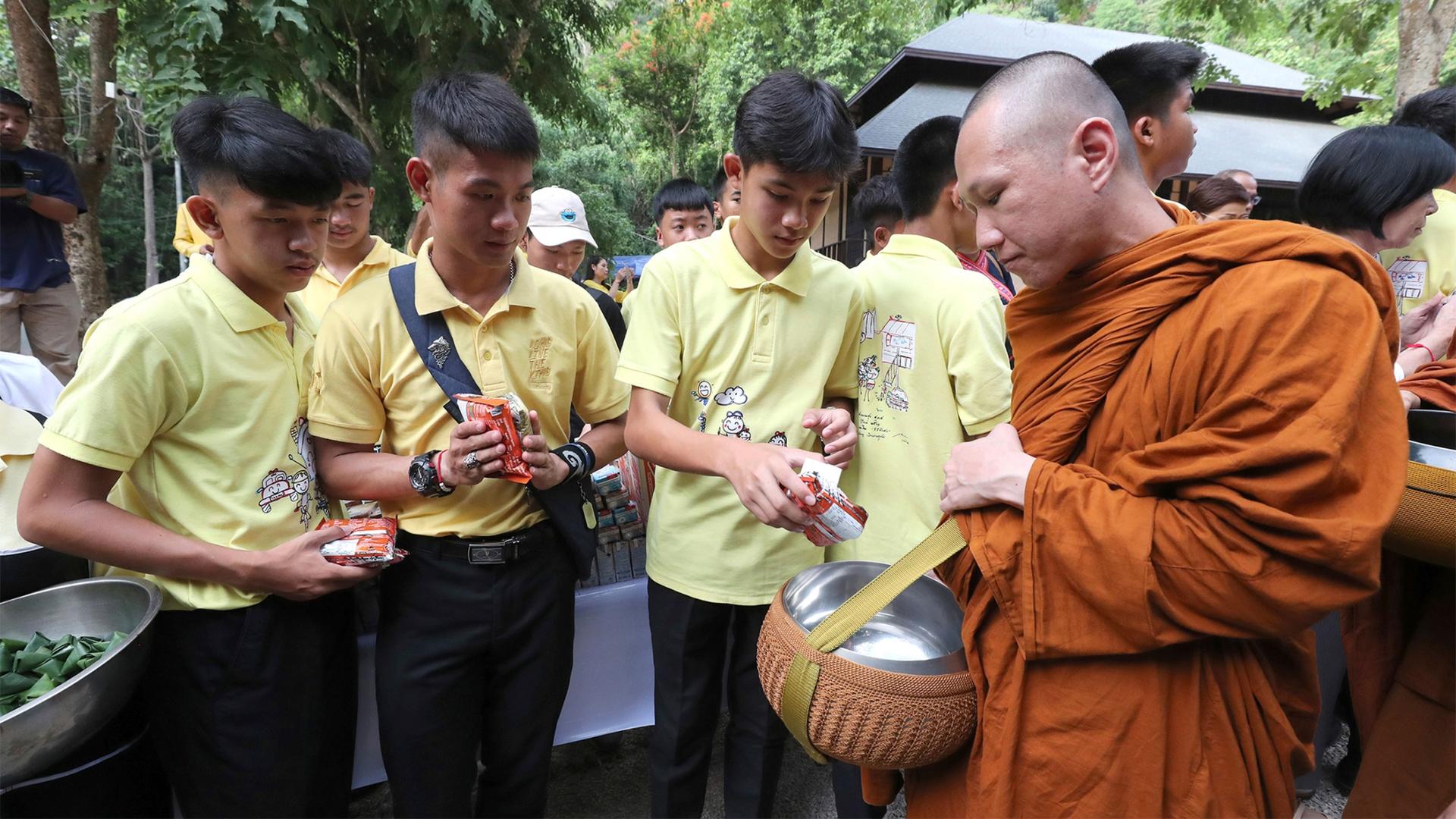 Members of the Wild Boars soccer team who were rescued from a flooded cave, offer foods to a Buddhist monk near the Tham Luang cave in Mae Sai, Chiang Rai province, Thailand, to mark one year since their rescue