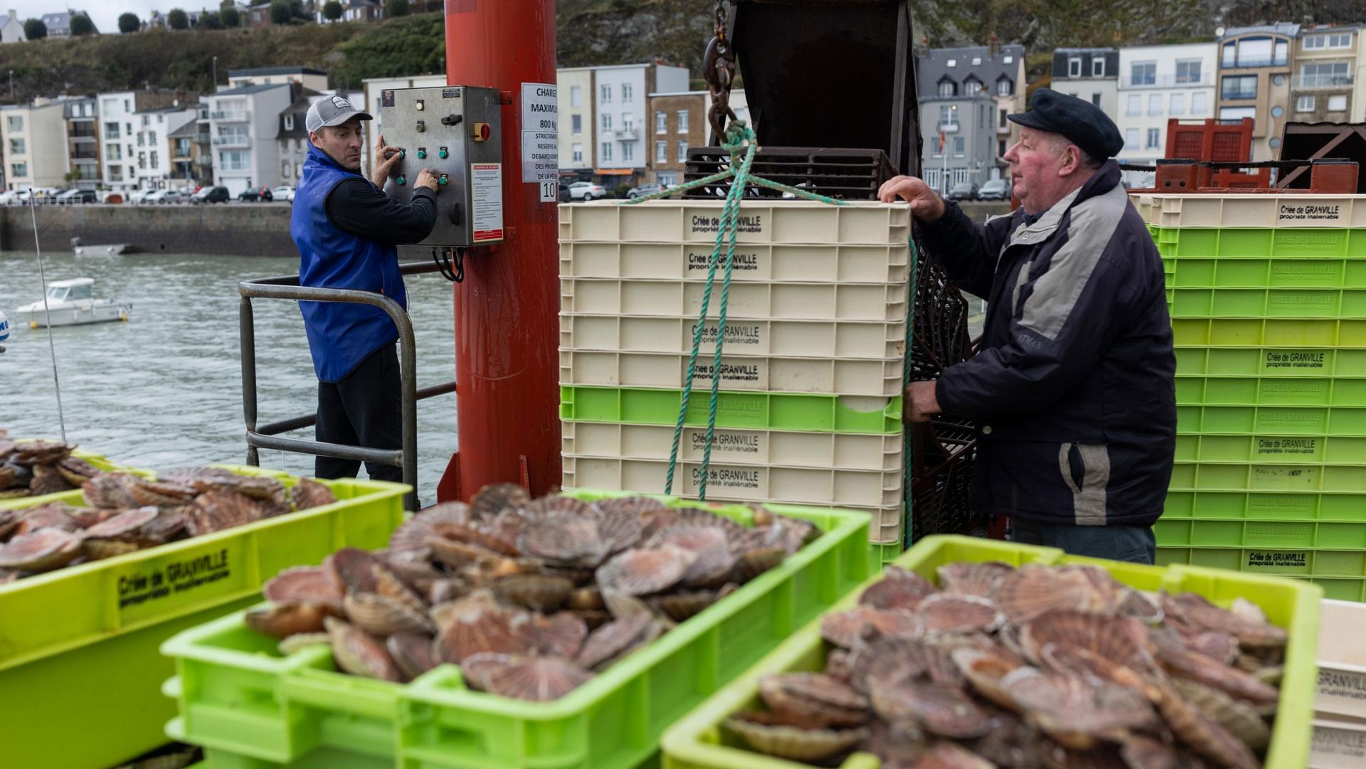 French fisherman Herman Outrequin, left, who does not have a license to fish in the UK waters, works the port of Granville, Normandy, Tuesday, Nov. 2, 2021.