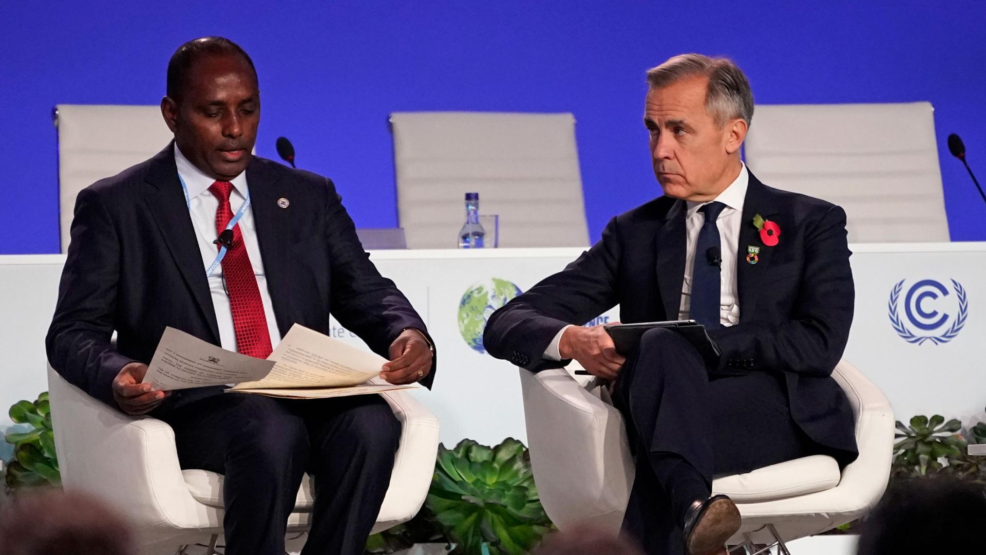 Kenyan Treasury Cabinet Secretary Ukur Yatani, left, and Mark Carney, the British Prime Minister Boris Johnson's Finance Adviser for COP26 and the UN Special Envoy for Climate Action and Finance sit on stage at the COP26 UN Climate Summit in Glasgow, Scot