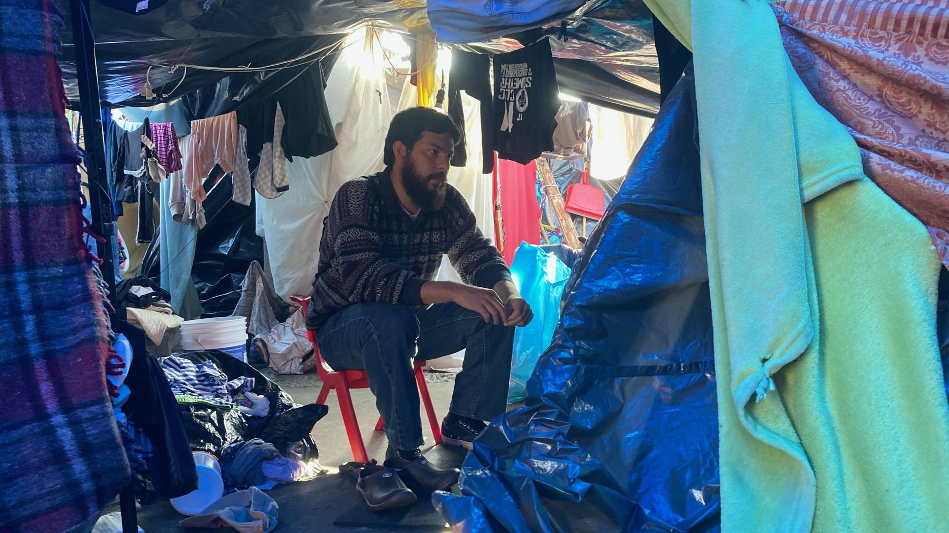 Psychologist Sebastián Farías speaks with asylum-seekers inside a migrant encampment on Nov. 6, 2021. 