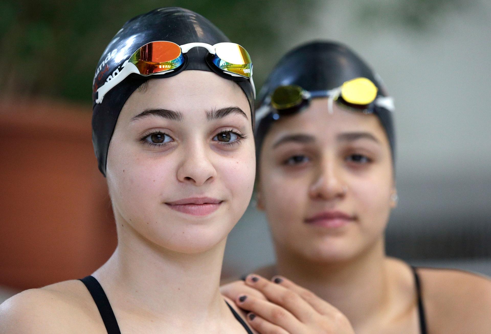 In this photo taken Monday, Nov. 9, 2015, Yusra Mardini, left, and her sister Sarah, right, from Syria pose for a photo during a training session in Berlin, Germany. The sisters were once swimming for their lives, after jumping off an inflatable boat that