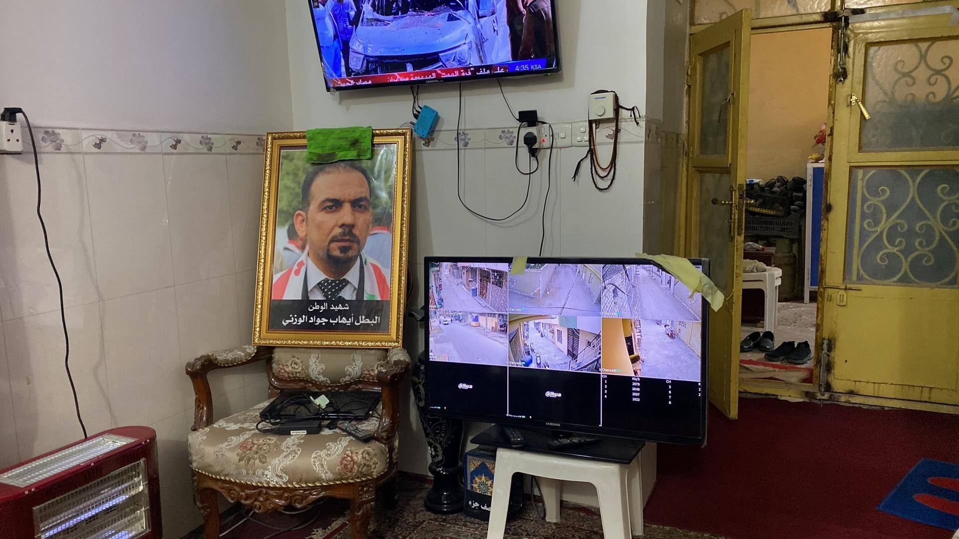 A portrait of slain Iraqi activist Ehab al-Wazni sits propped up in a chair in his family’s living room in Karbala, Iraq. Atop it is a rag of dried blood and next to it is a TV monitor with security camera footage, Dec. 7, 2021. 