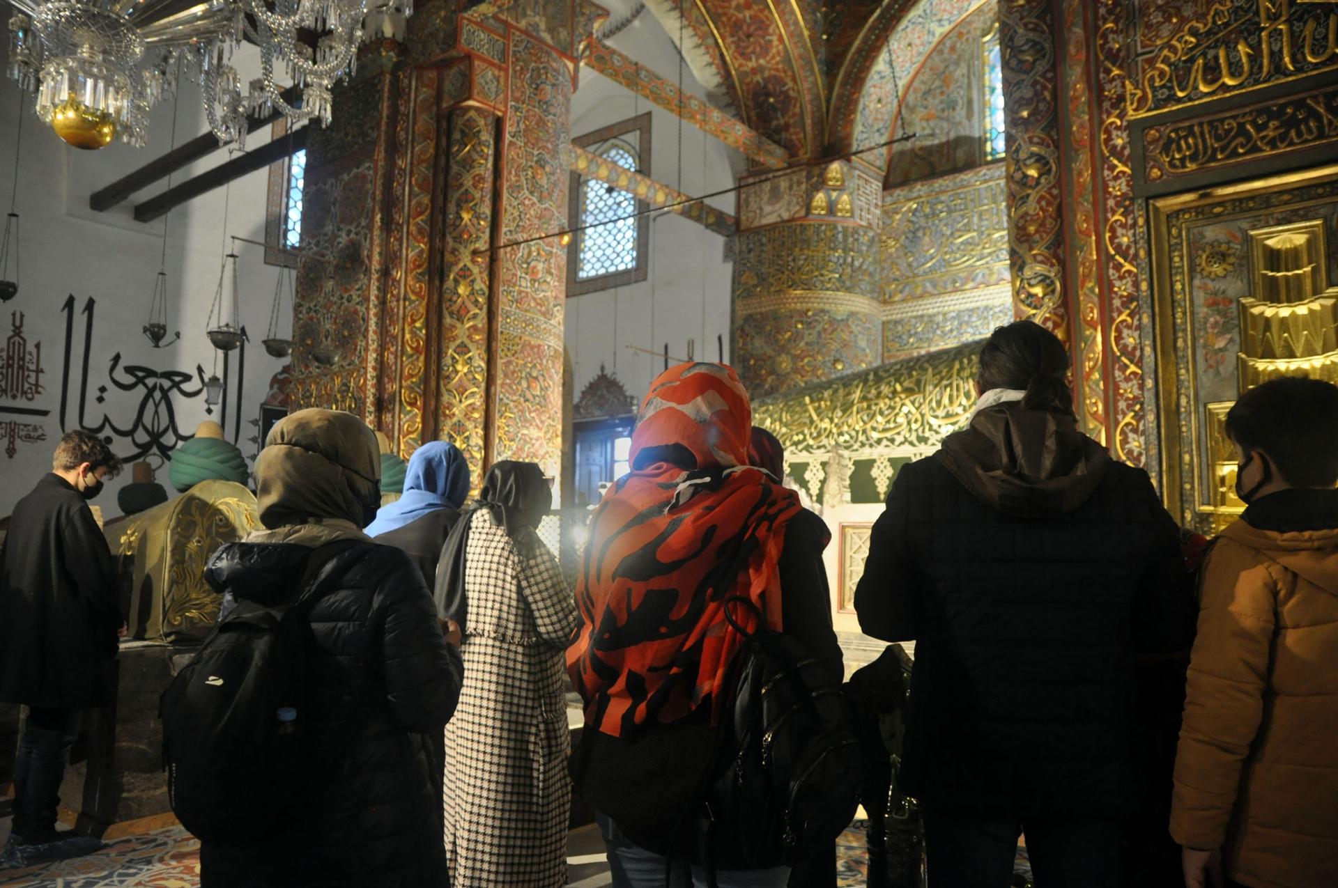 Visitors pray before the green tomb of Rumi. 