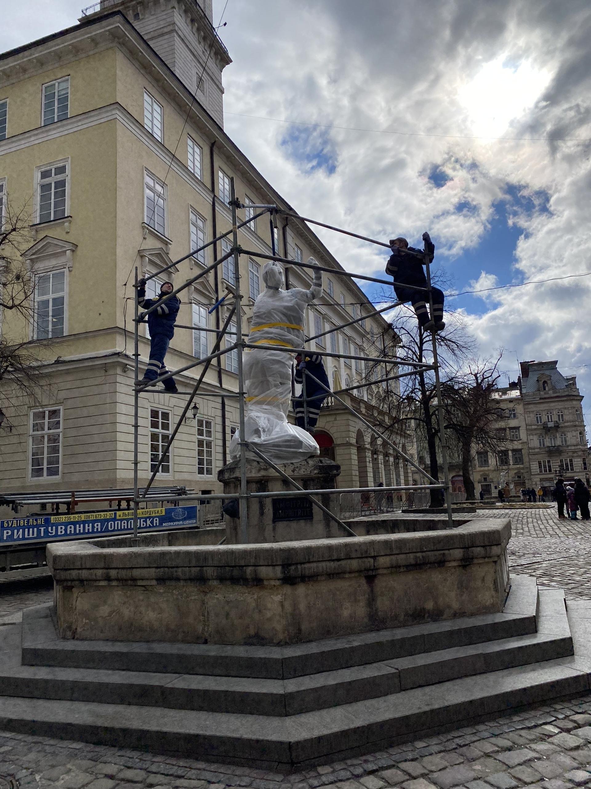 Workers construct metal scaffolding around the statue of Greek goddess Amphitrite in Lviv's medieval Market Square
