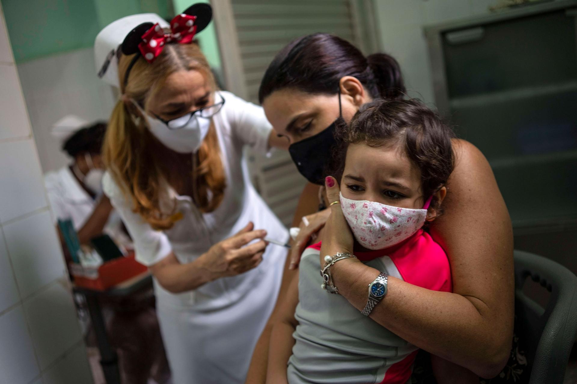 A mother holds her daughter who is injected with a dose of the Soberana-02 COVID-19 vaccine, in Havana, Cuba, Thursday, Sept. 16, 2021. 