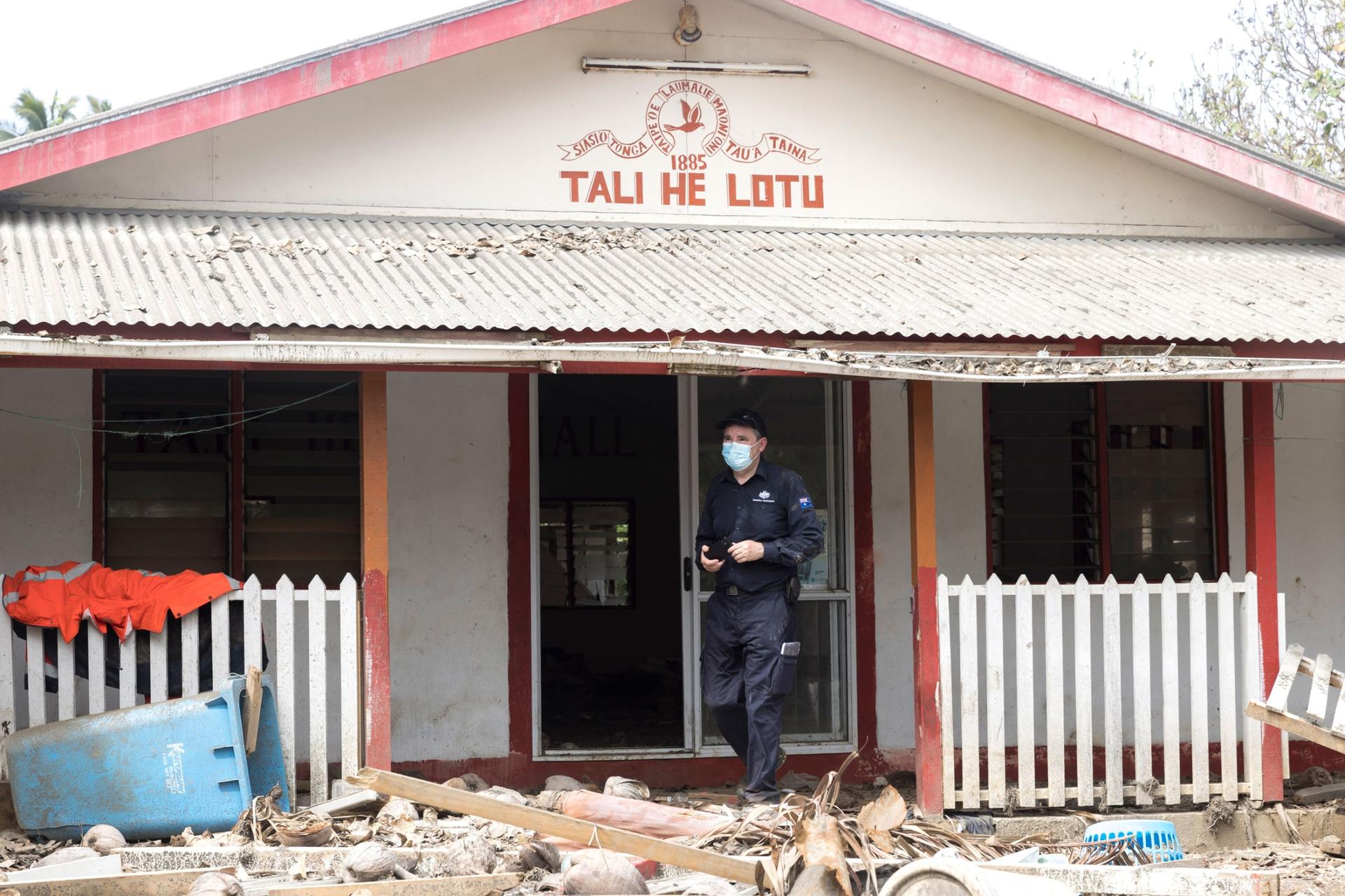 In this photo provided by the Australian Defense Force, an officer of Department of Foreign Affairs & Trade Crisis response team assesses damage to Atata island, in Nuku'alofa, Tonga, following the eruption of underwater volcano, on Feb. 4, 2022.