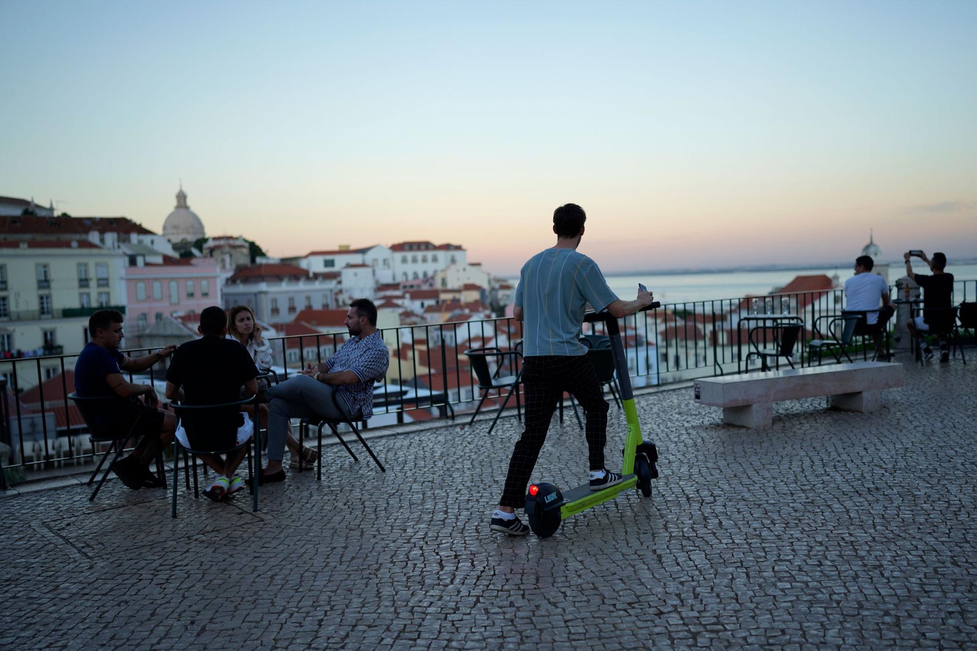 A man uses an electric scooter at a viewpoint overlooking the old Alfama neighborhood in Lisbon, Wednesday, Oct. 6, 2021. 