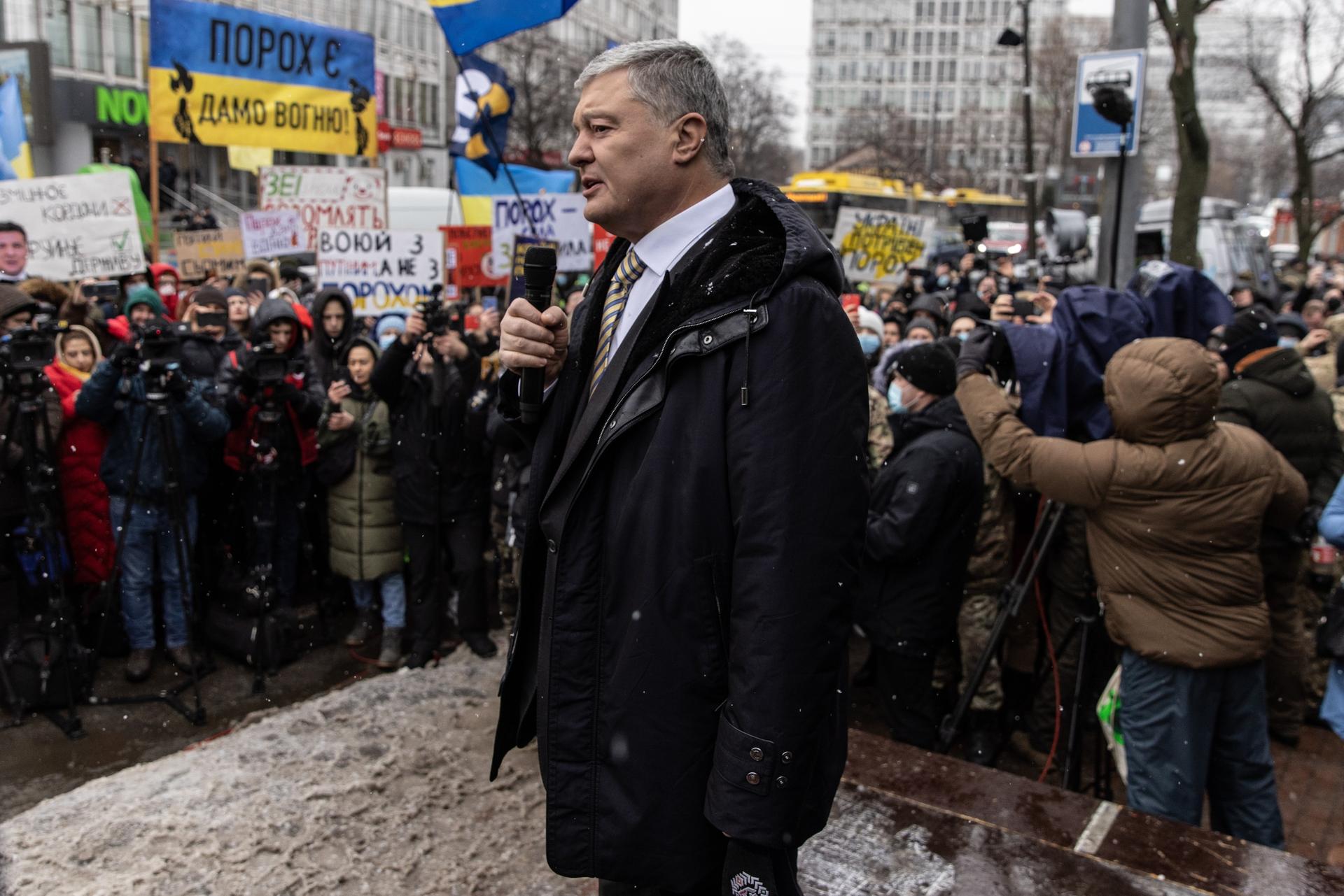Petro Poroshenko standing among a crowd as it snows 